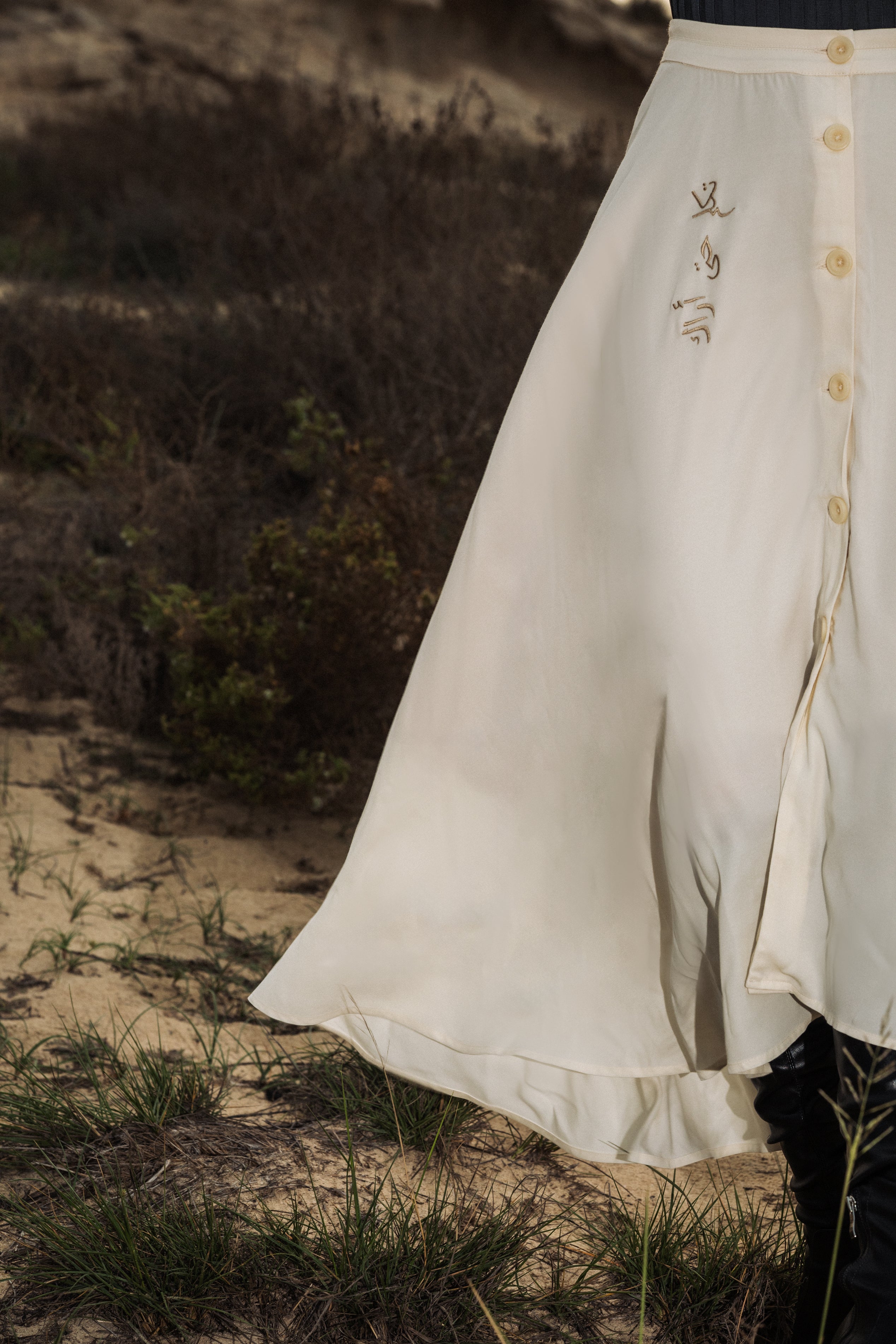 The omni the label skirt in cream white with arabic embroidery on the side and buttons UAE, KSA, Qatar
