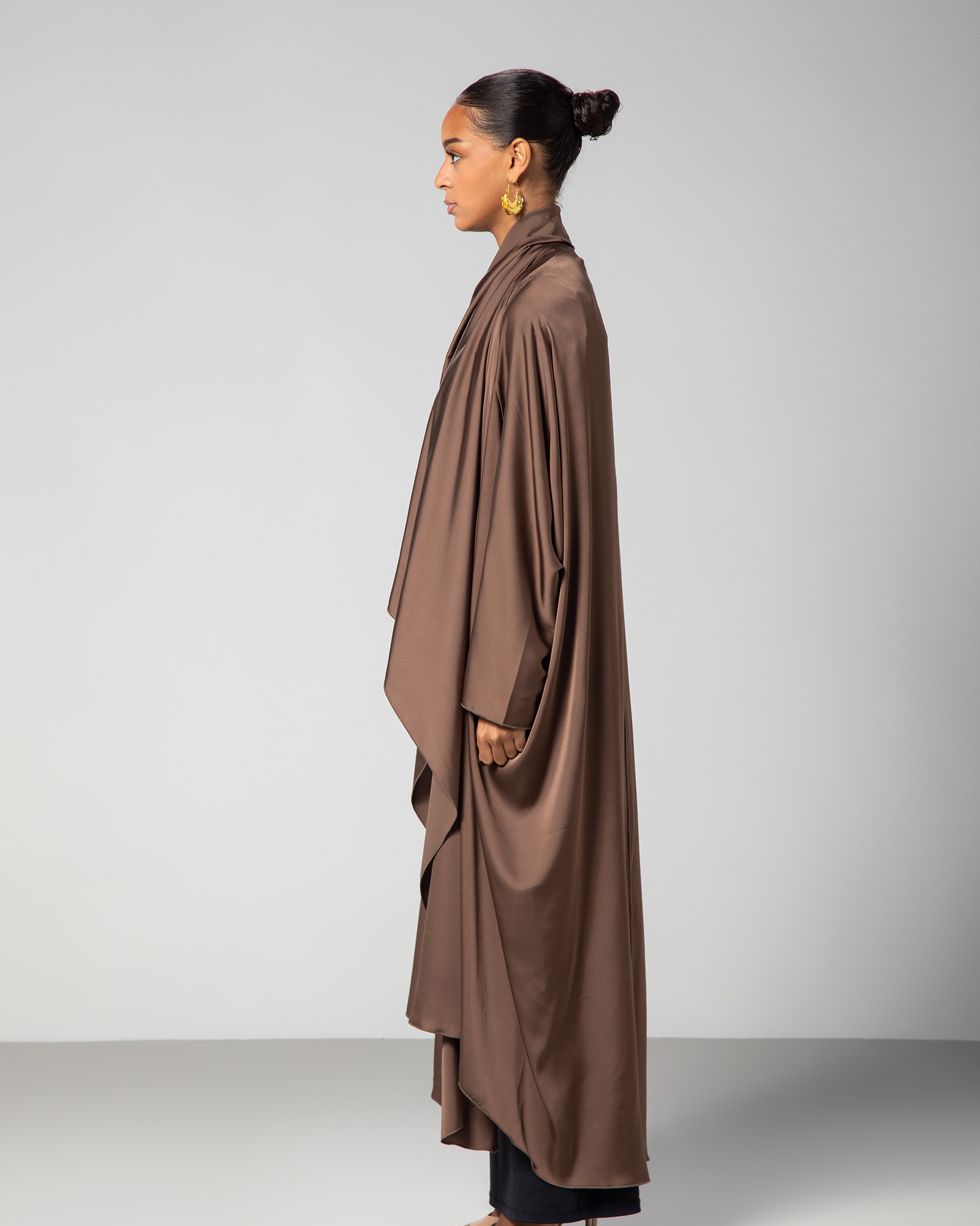 Side view of the Flow Abaya in brown, emphasizing the flowy silhouette and a glimpse of the Arabic embroidery across the front KSA UAE Qatar