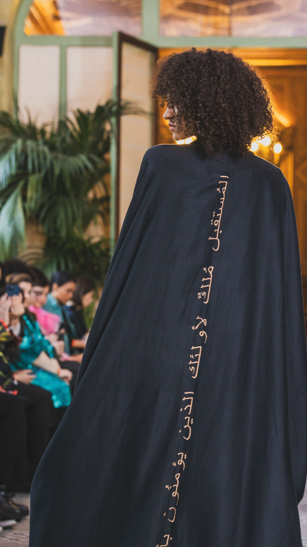 Gold Arabic calligraphy embroidery on black Abaya with classic sleeves worn on runway Paris Fashion Week Omni The Label Qatar KSA UAE