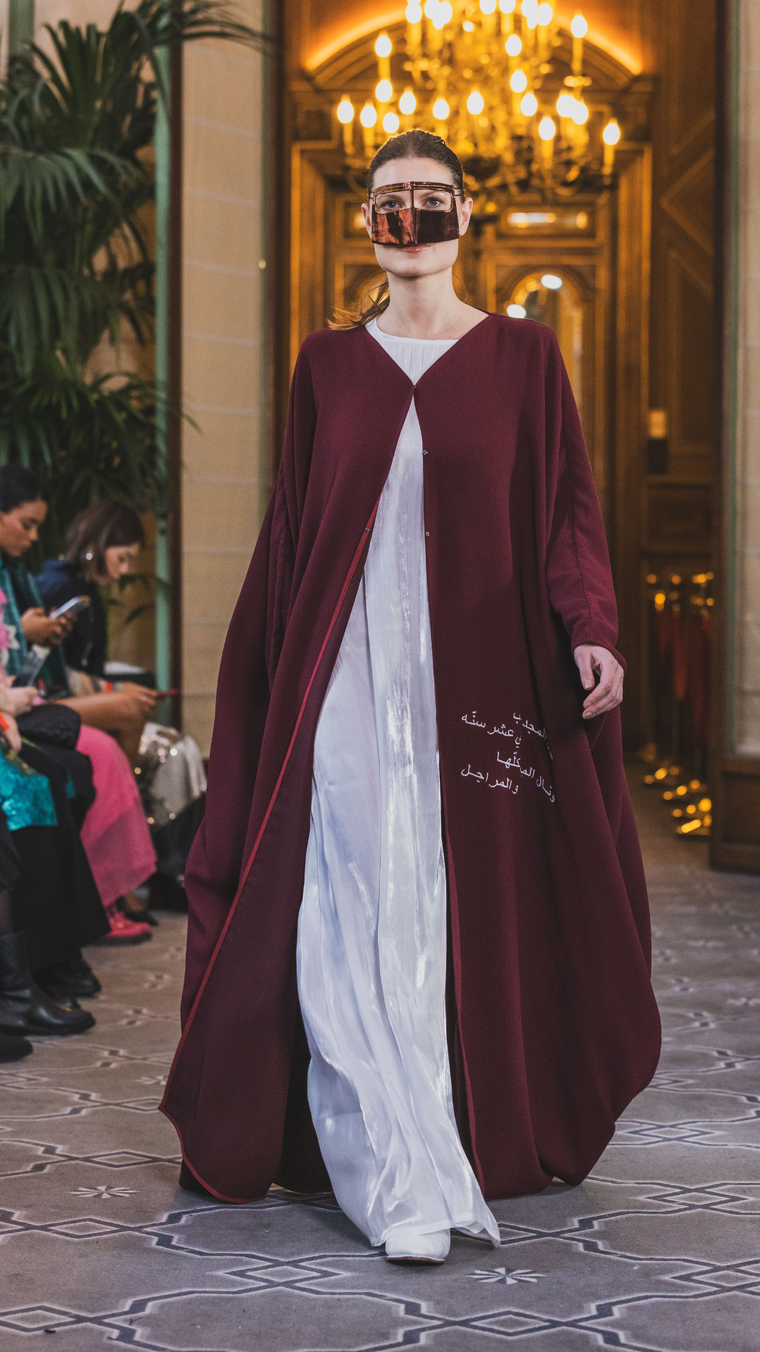 Model wearing burgundy Qatar National Day Abaya outdoors with gold headpiece and white inner dress – UAE, KSA, Qatar