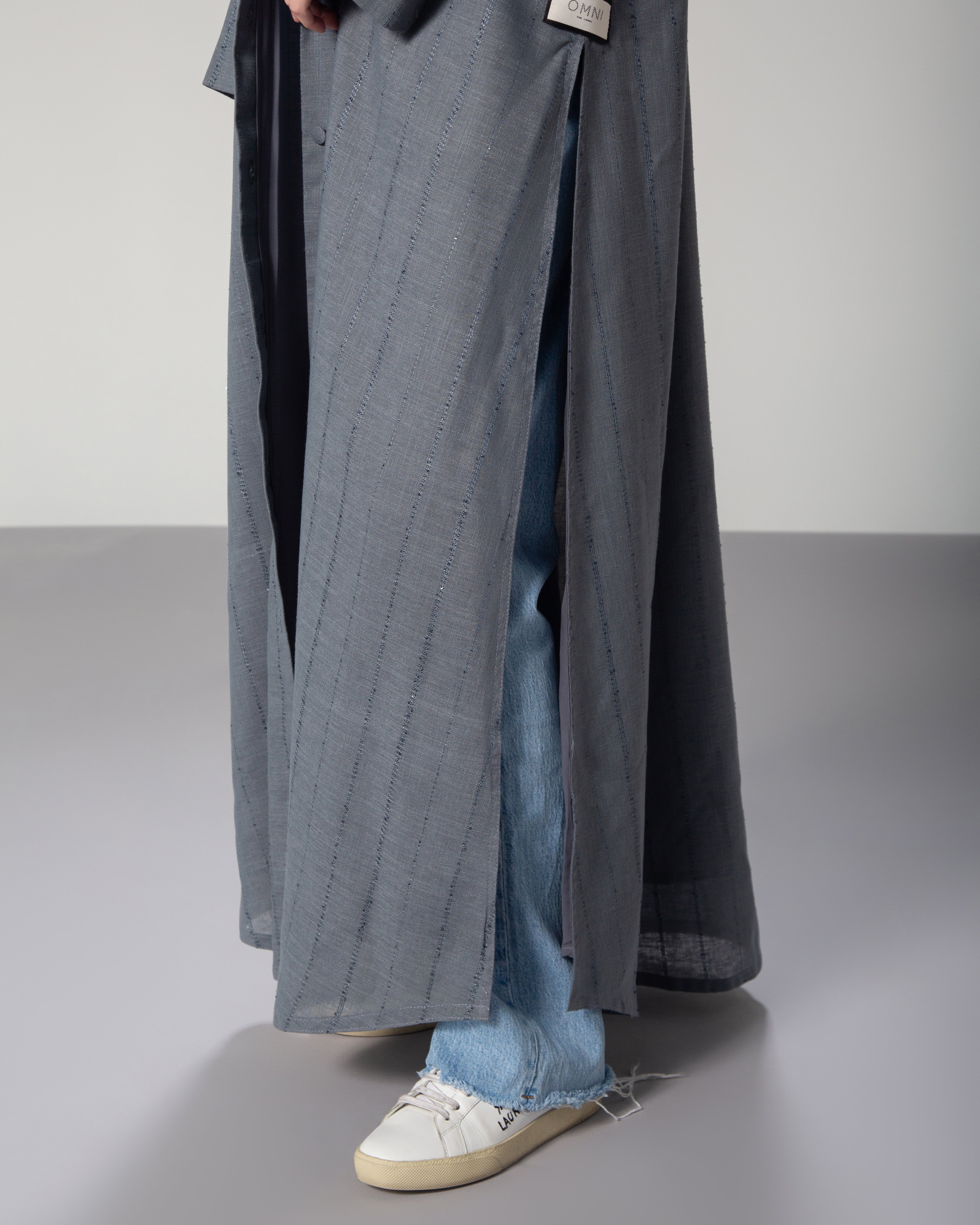 A woman wearing a blue linen collared abaya with sequins, featuring a A-line cut and fabric-covered buttons middle east saudi kuwait qatar modest fashion