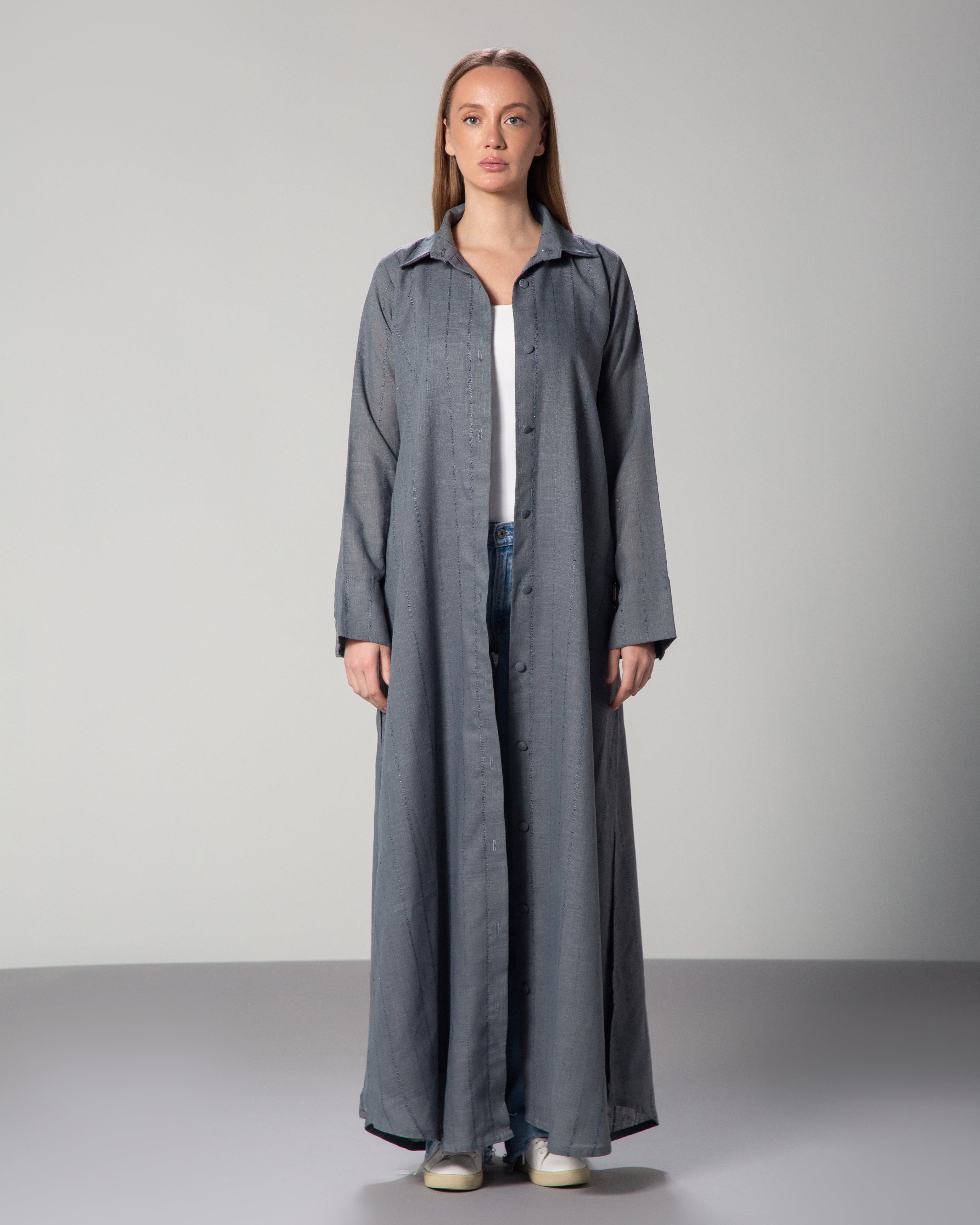 A woman wearing a blue linen collared abaya with sequins, featuring a A-line cut and fabric-covered buttons, middle east saudi kuwait qatar modest fashion