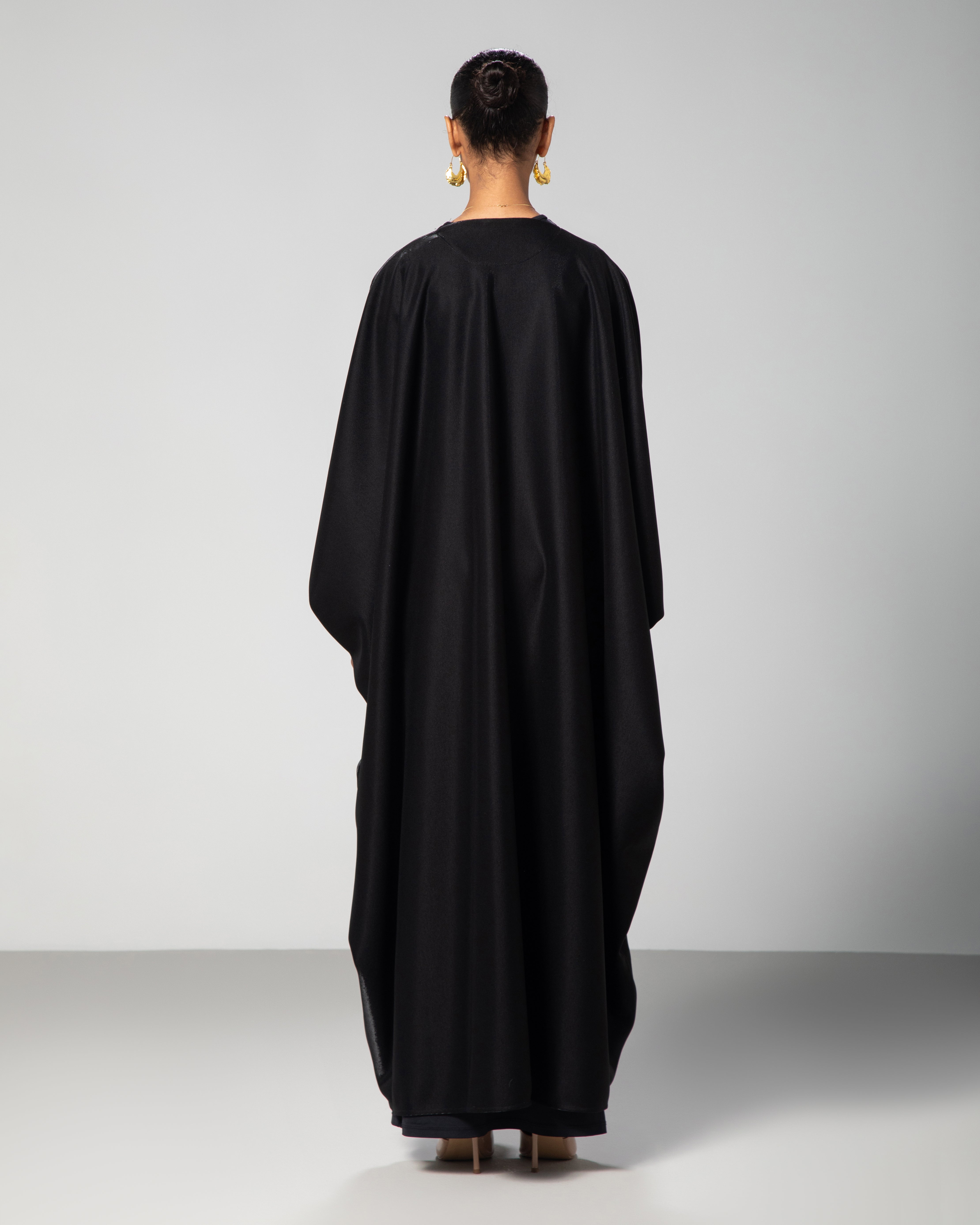 Premium black abaya with subtle shine, crafted for elegant modest fashion — model showcase by Omni The Label KSA UAE Qatar
