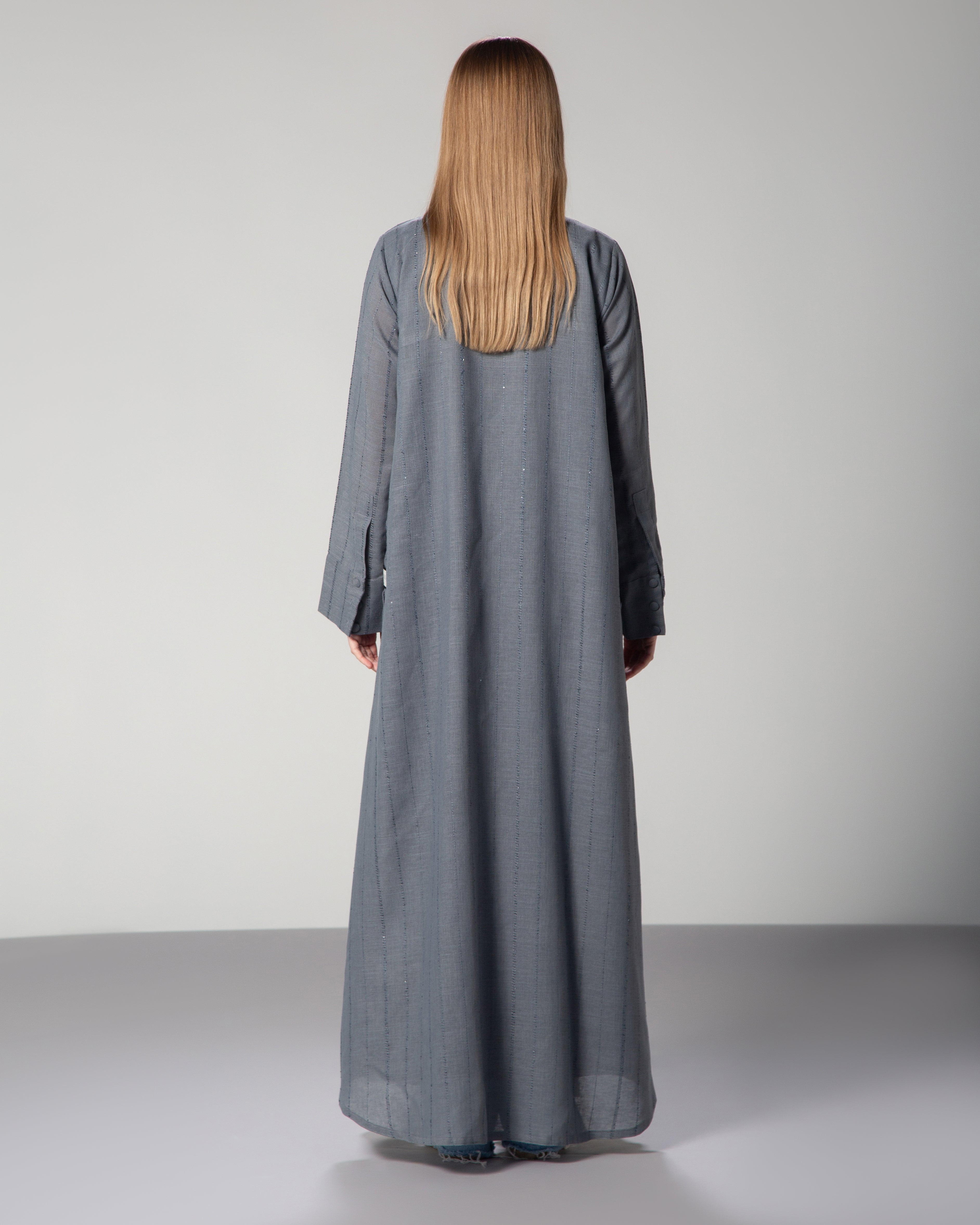 A woman wearing a blue linen collared abaya with sequins, featuring a A-line cut and fabric-covered buttons middle east saudi kuwait qatar modest fashion middle east saudi kuwait qatar modest fashion