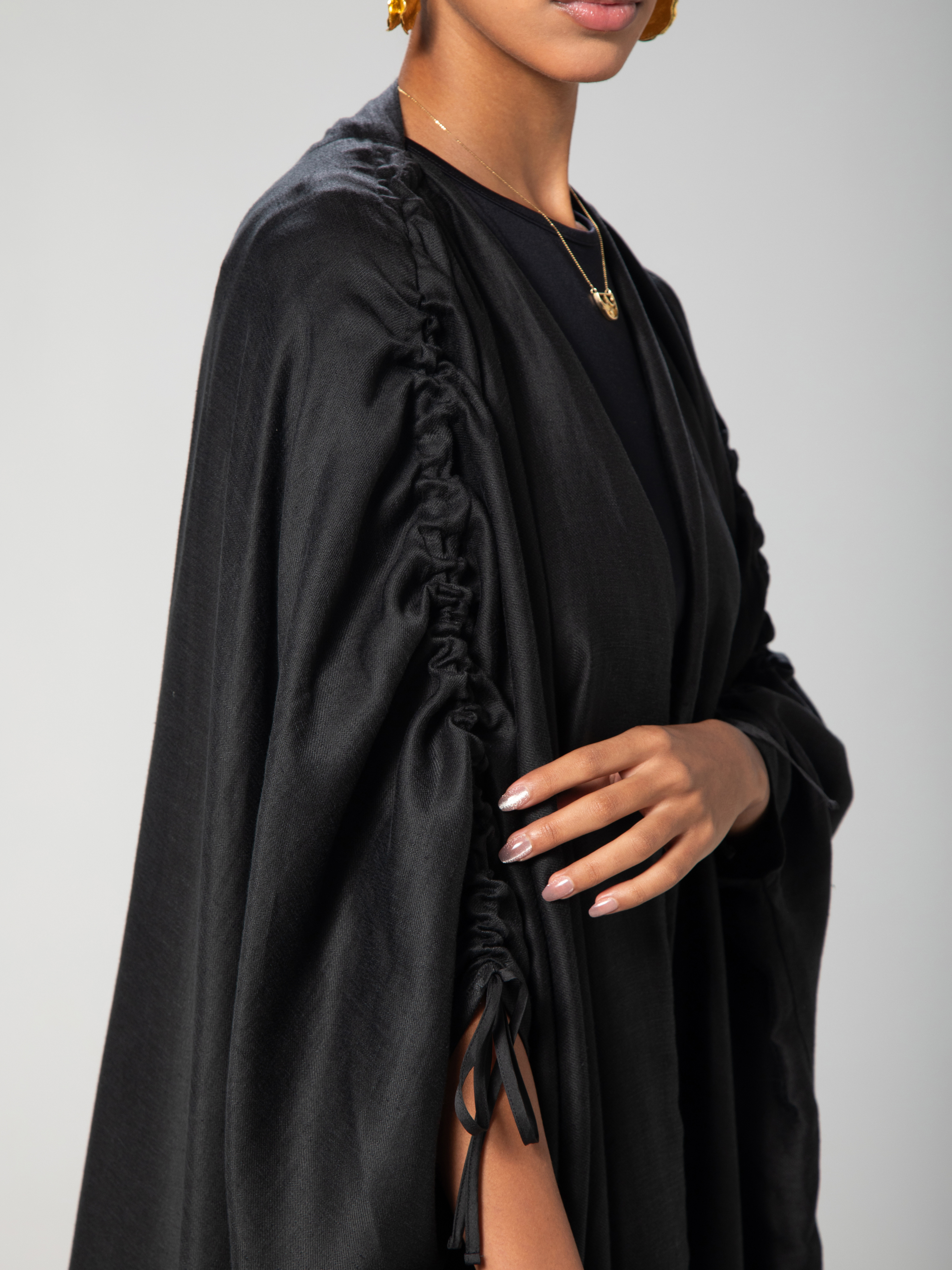 a black abaya with adjiustable sleeves with arabic caligraphy embroidered on the back by omni the label