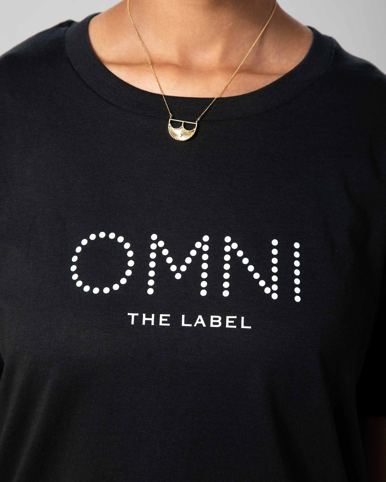 etailed front view of the black T-shirt showing Omni The Label logo printed across the chest in minimalist white font.