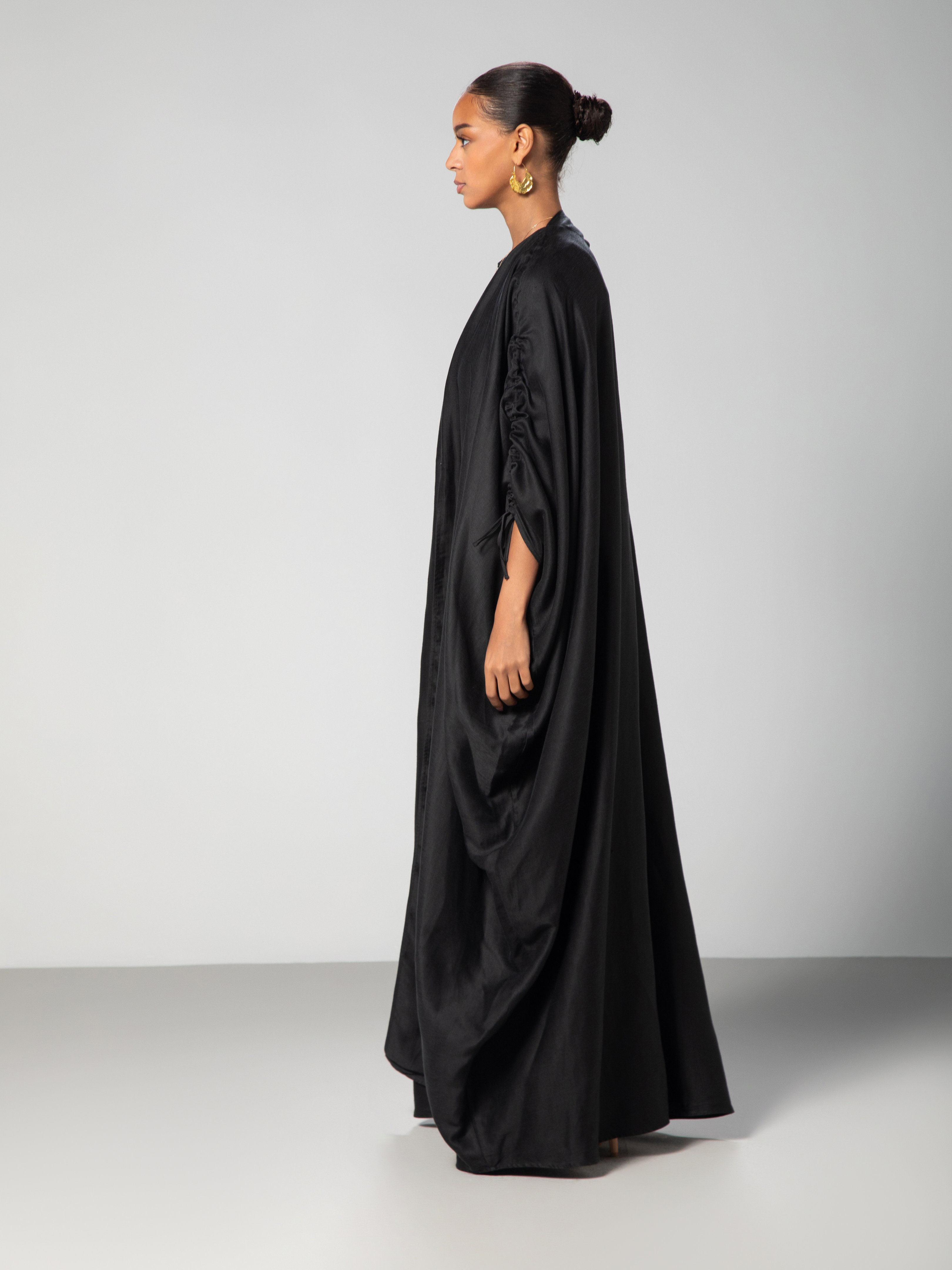 Black abaya with adjustable sleeves Arabic calligraphy embroidery on the back studio side view Omni The Label KSA UAE Qatar