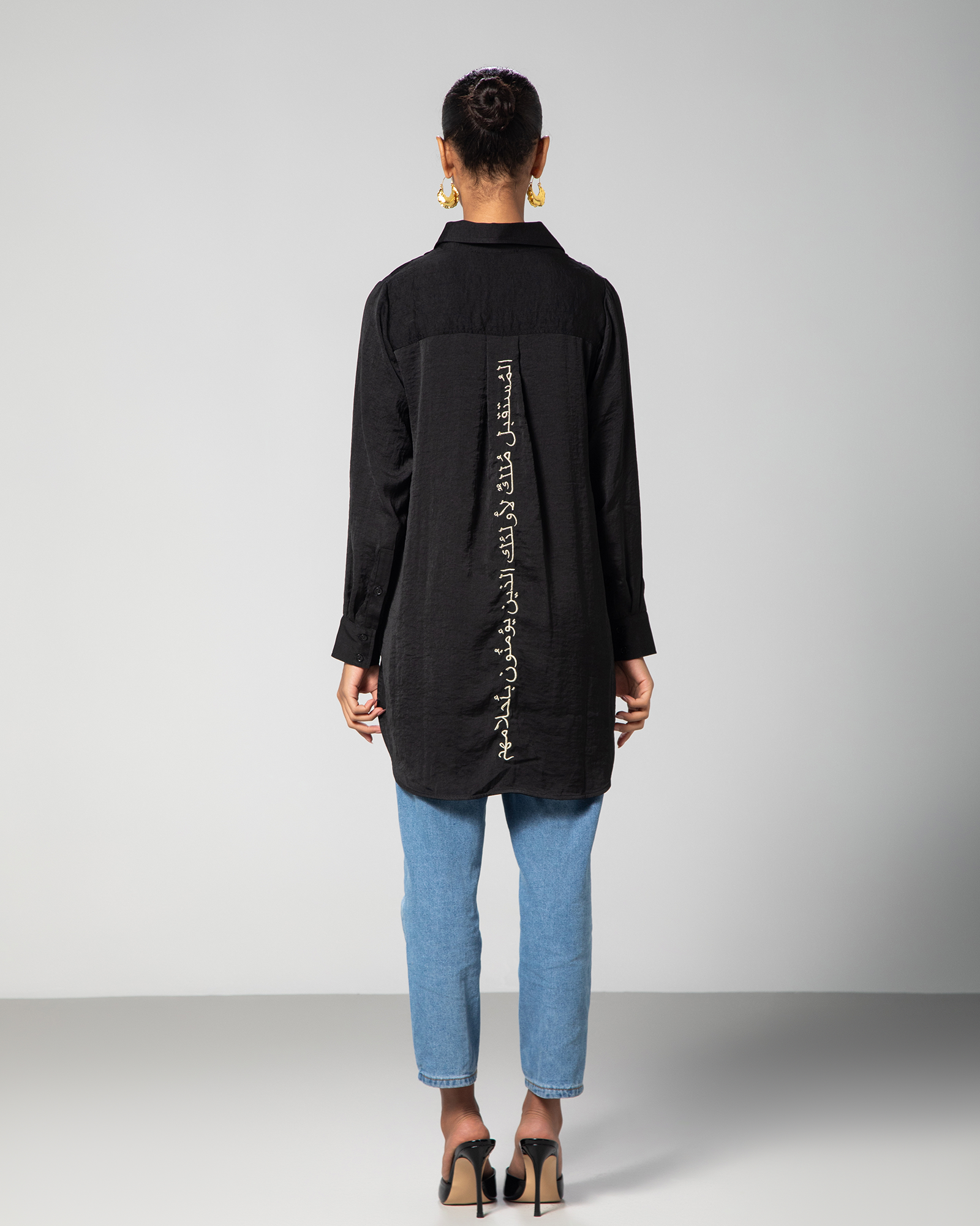 Back view of black collared shirt by Omni The Label showcasing gold Arabic embroidery reading “The future belongs to those who believe in their dreams” – UAE, KSA, Qatar