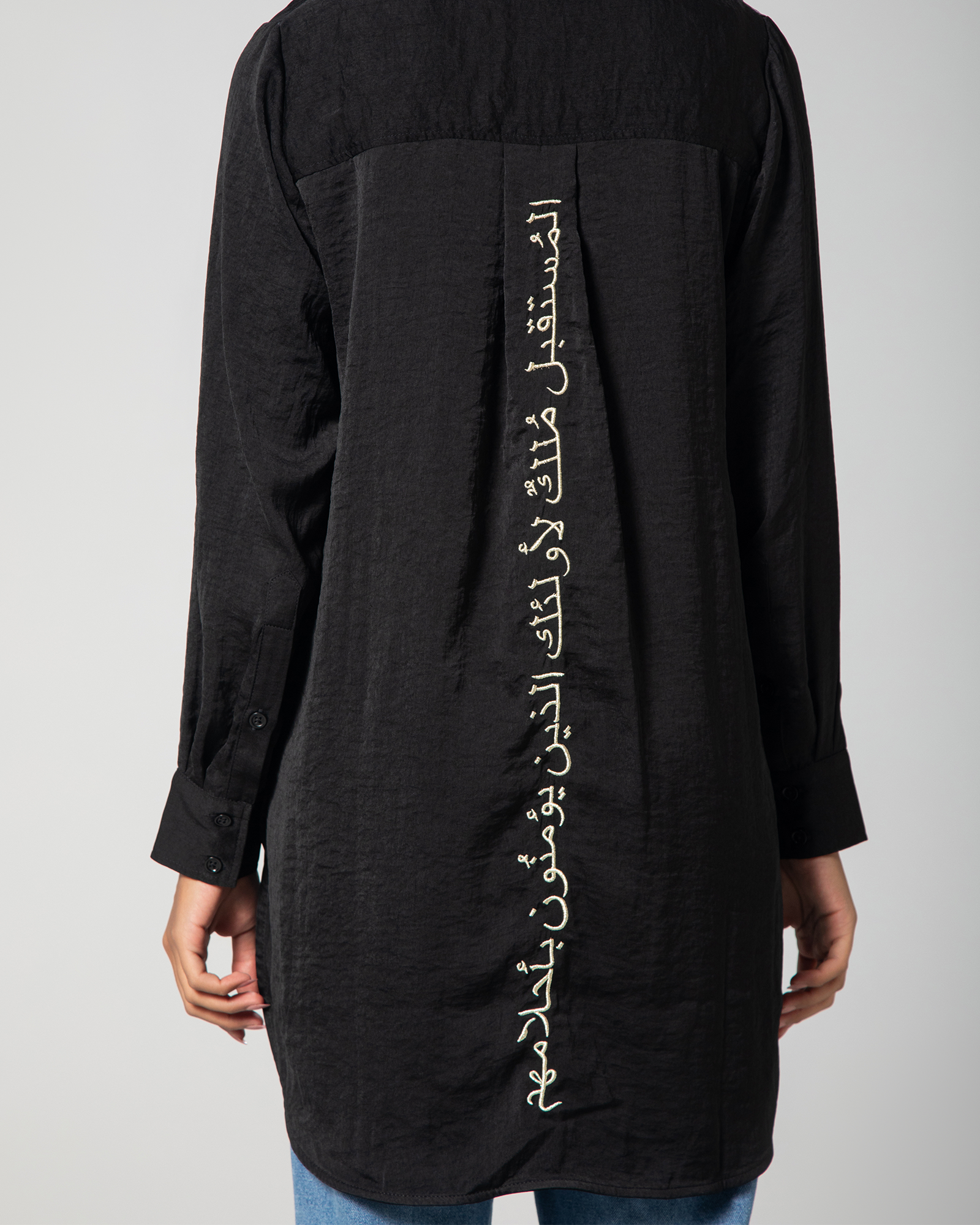 Close-up of the gold-thread Arabic embroidery on the back of Omni The Label’s black shirt – UAE, KSA, Qatar