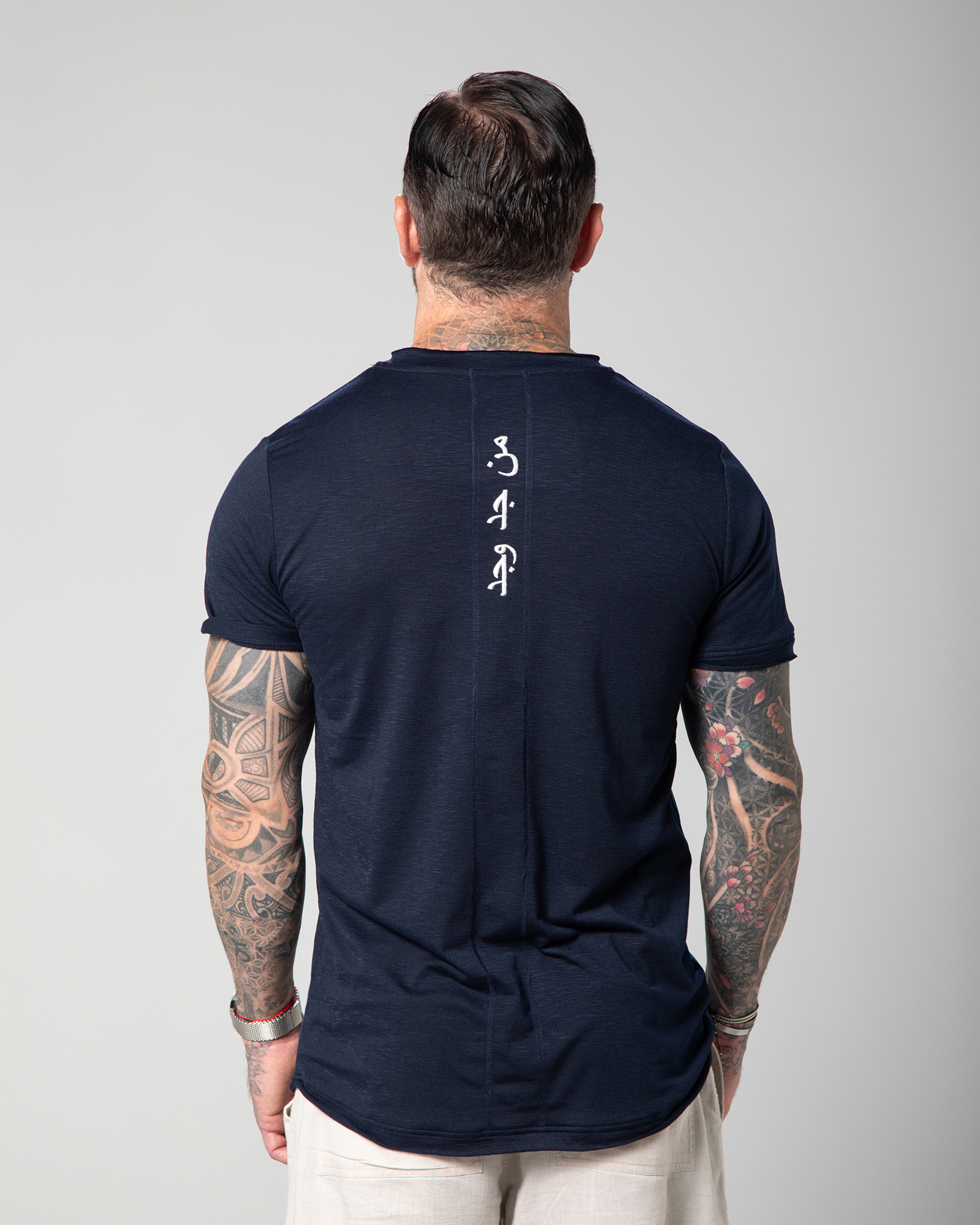 Omni The Label’s blue men’s T-shirt featuring “Who seeks, finds” Arabic embroidery along the back seam, combining comfort with intentional design UAE KSA Qatar