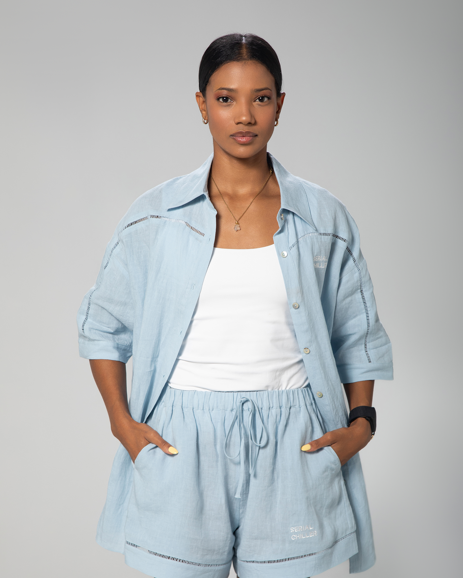Light blue linen shirt and shorts set for women by Omni The Label, styled on model against neutral studio background UAE KSA Qatar