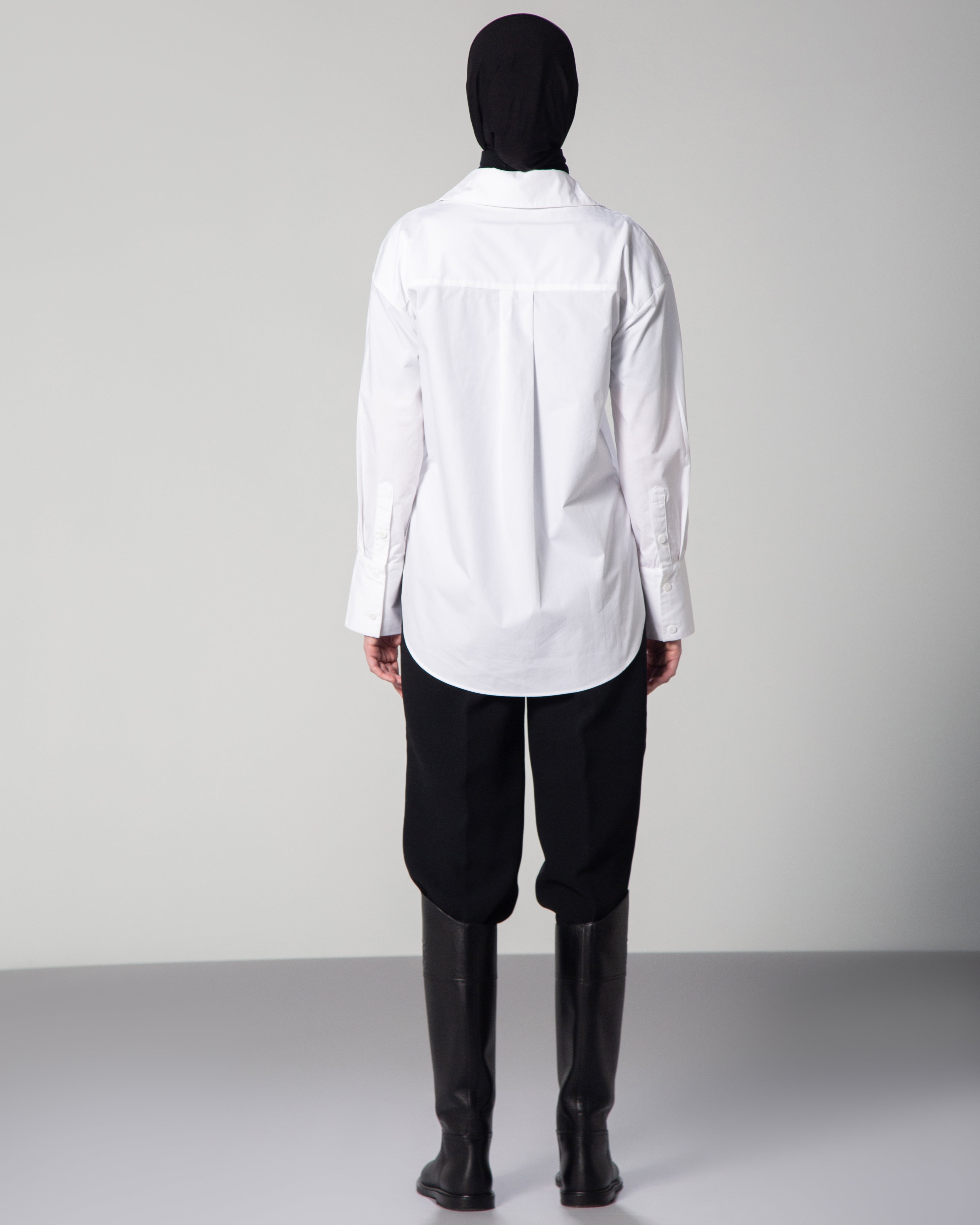 Minimalist white cotton poplin shirt for women – OMNI The Label fashion piece styled with black hijab on gray backdrop ksa Qatar