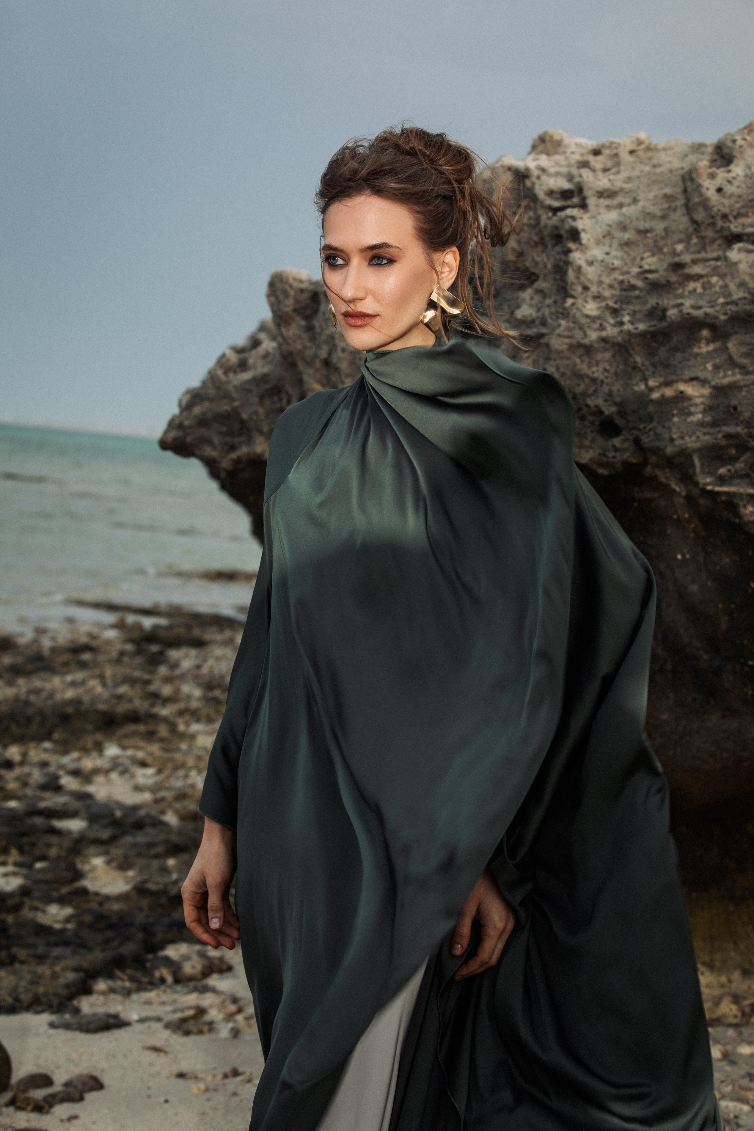 Omni The Label’s Flow Abaya in green worn near stone landscape, styled confidently – UAE, KSA, Qatar