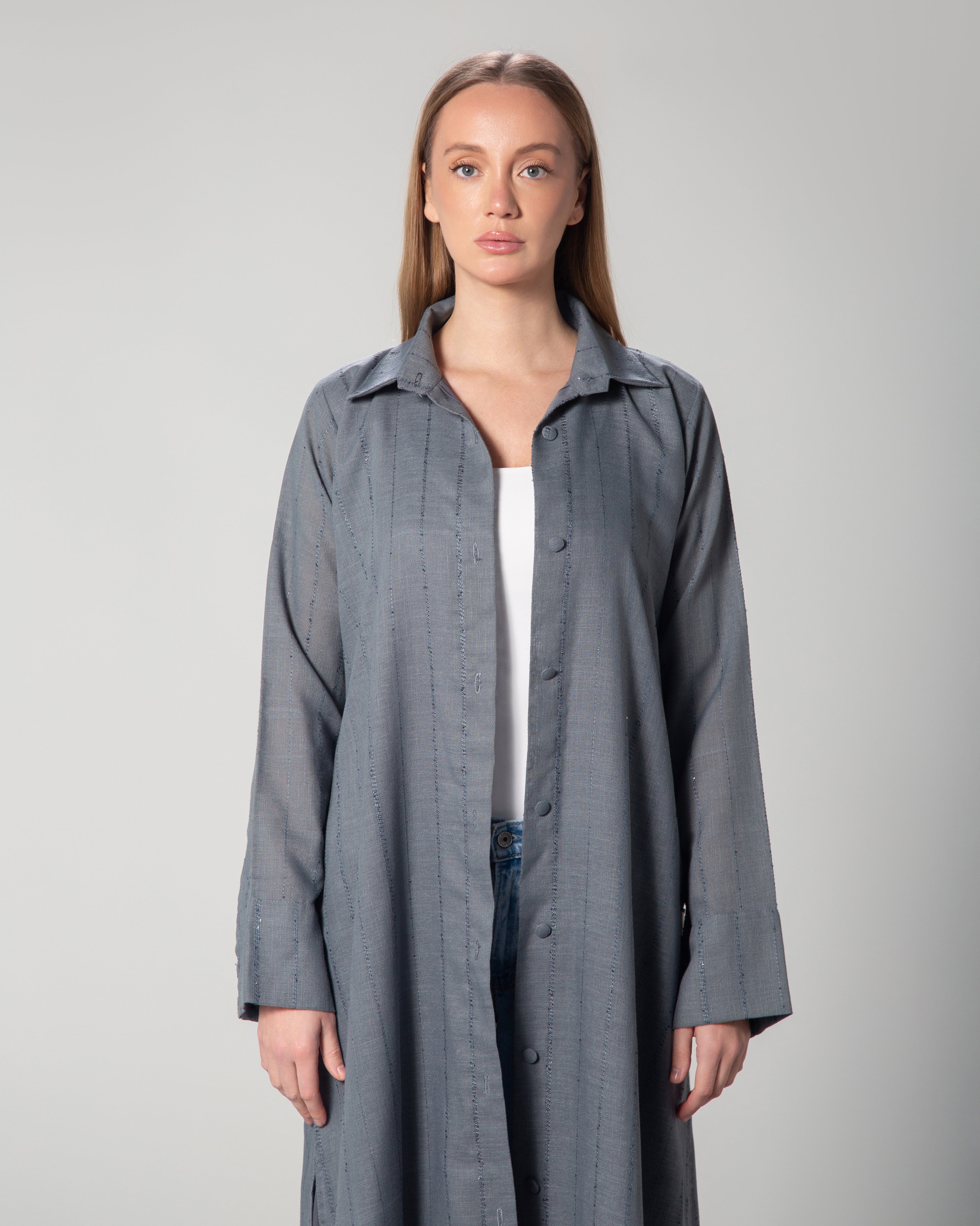 A woman wearing a blue linen long sleeve collared cover up with sequins , featuring a A-line cut and fabric-covered buttons middle east saudi kuwait qatar modest fashion
