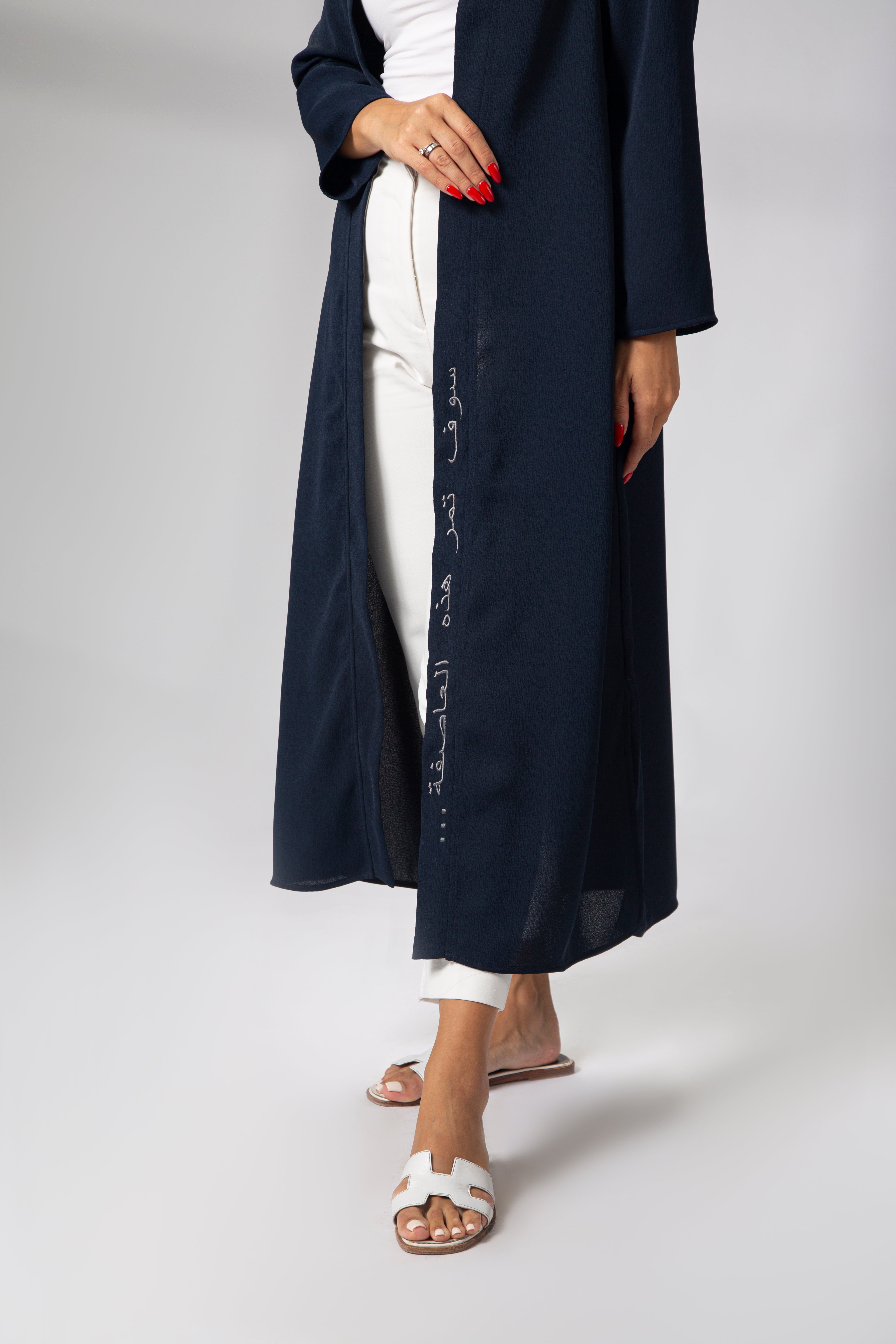 Model in motion showcasing the flowy silhouette of the navy blue kimono with embroidered Arabic quote on the front"This too shall pass..." KSA UAE Qatar