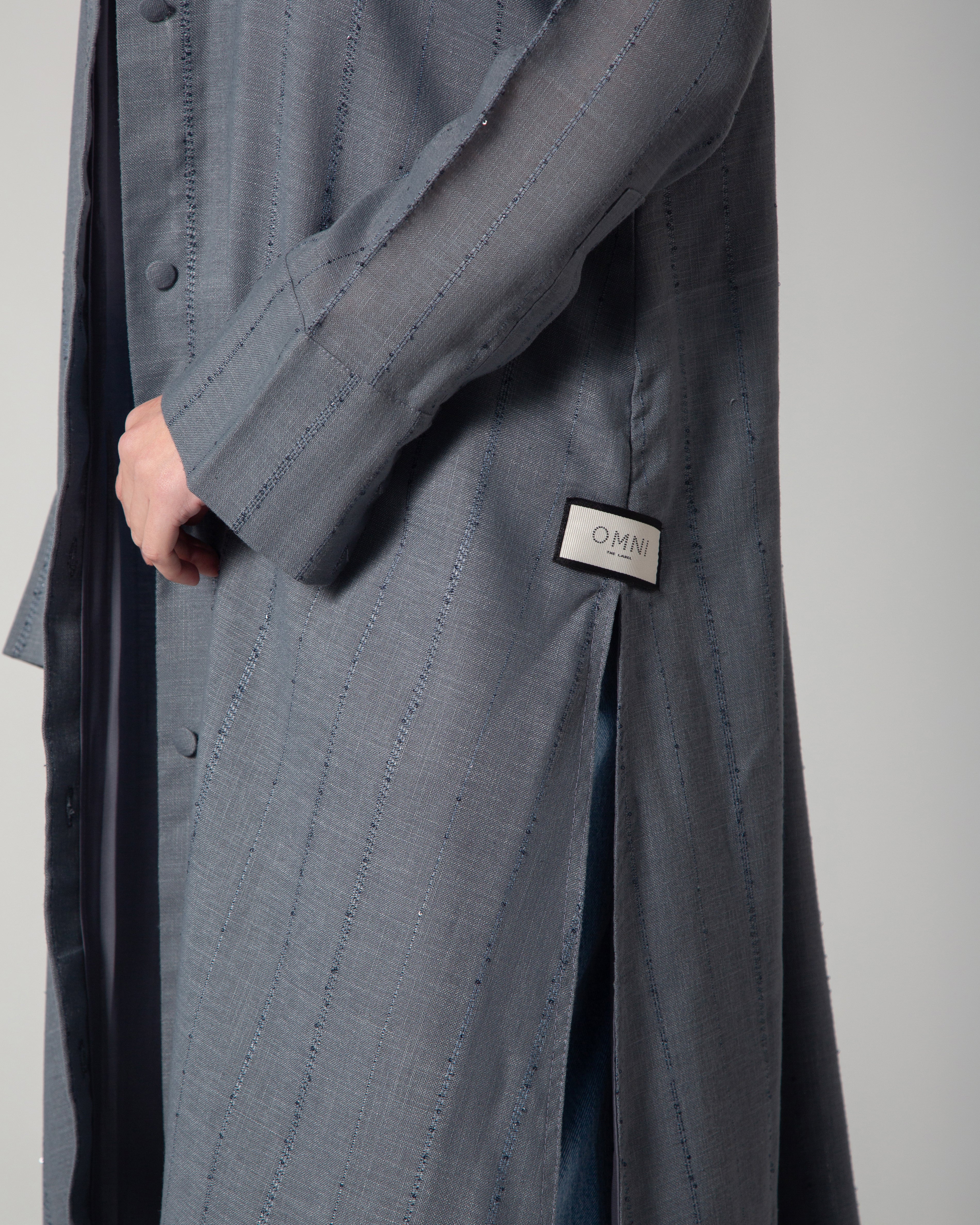 A woman wearing a blue linen collared abaya with sequins, featuring a A-line cut and fabric-covered buttons, middle east saudi kuwait qatar modest fashion
