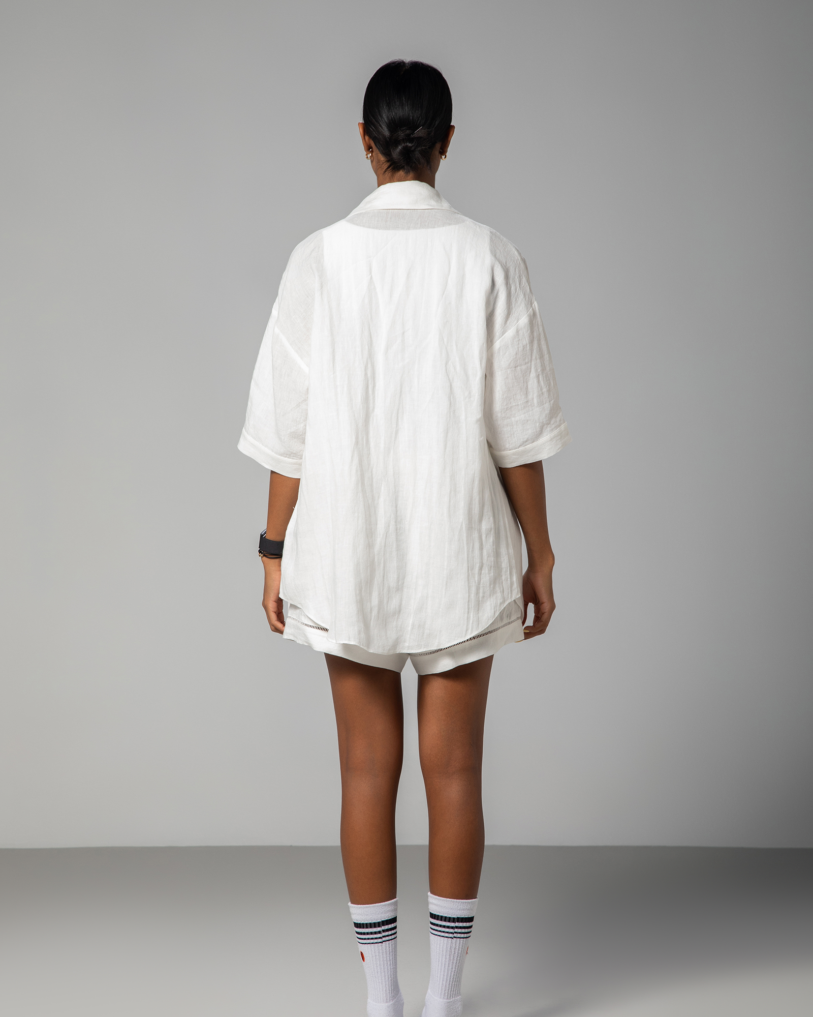 Back view of white linen shirt and shorts set from Omni The Label, showcasing loose tailoring and minimalist silhouette.UAE, KSA, Qatar