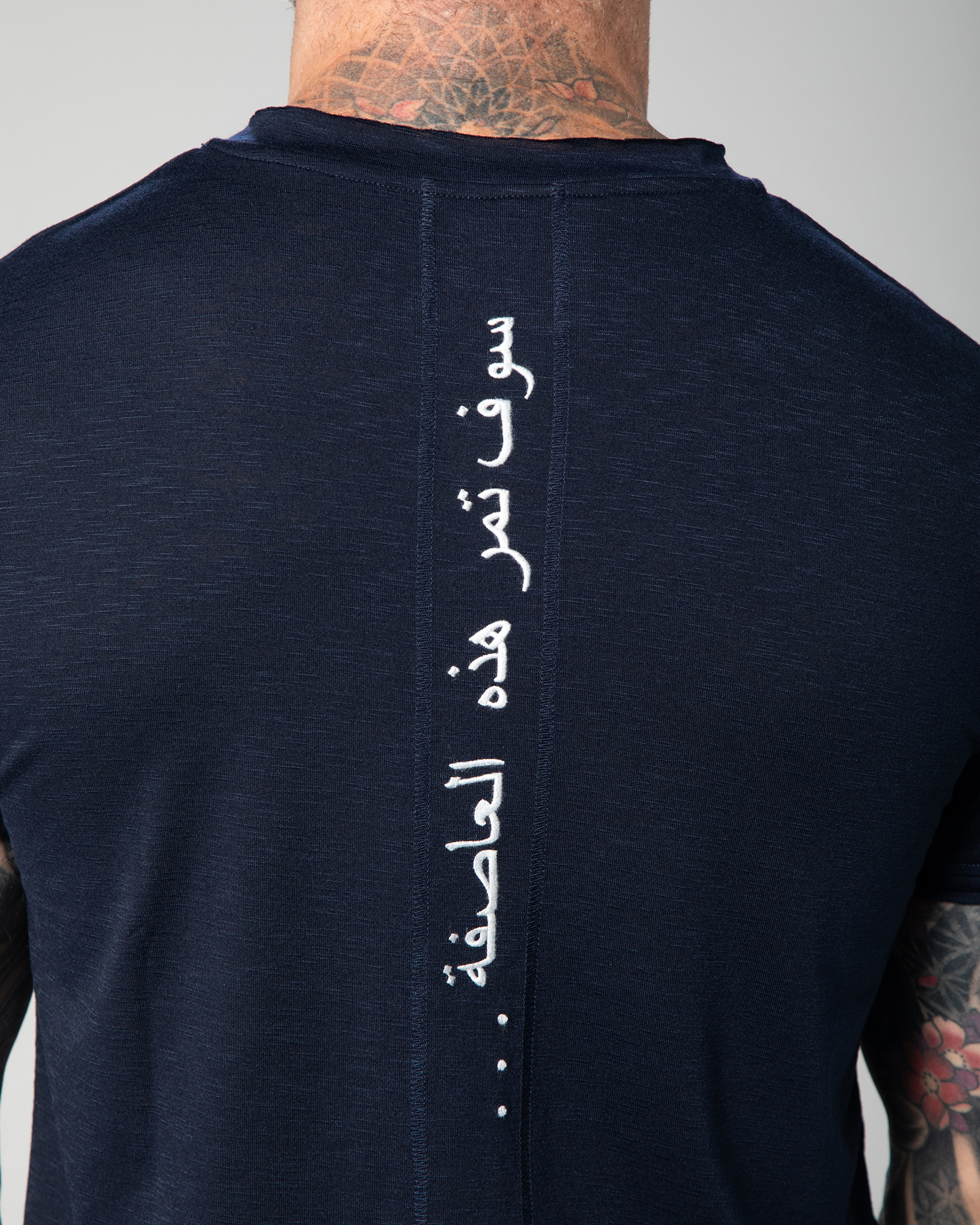Blue Marbella V-neck T-shirt shown from the back, featuring the phrase “This too shall pass” embroidered in Arabic calligraphy along the spineUAE KSA Qatar
