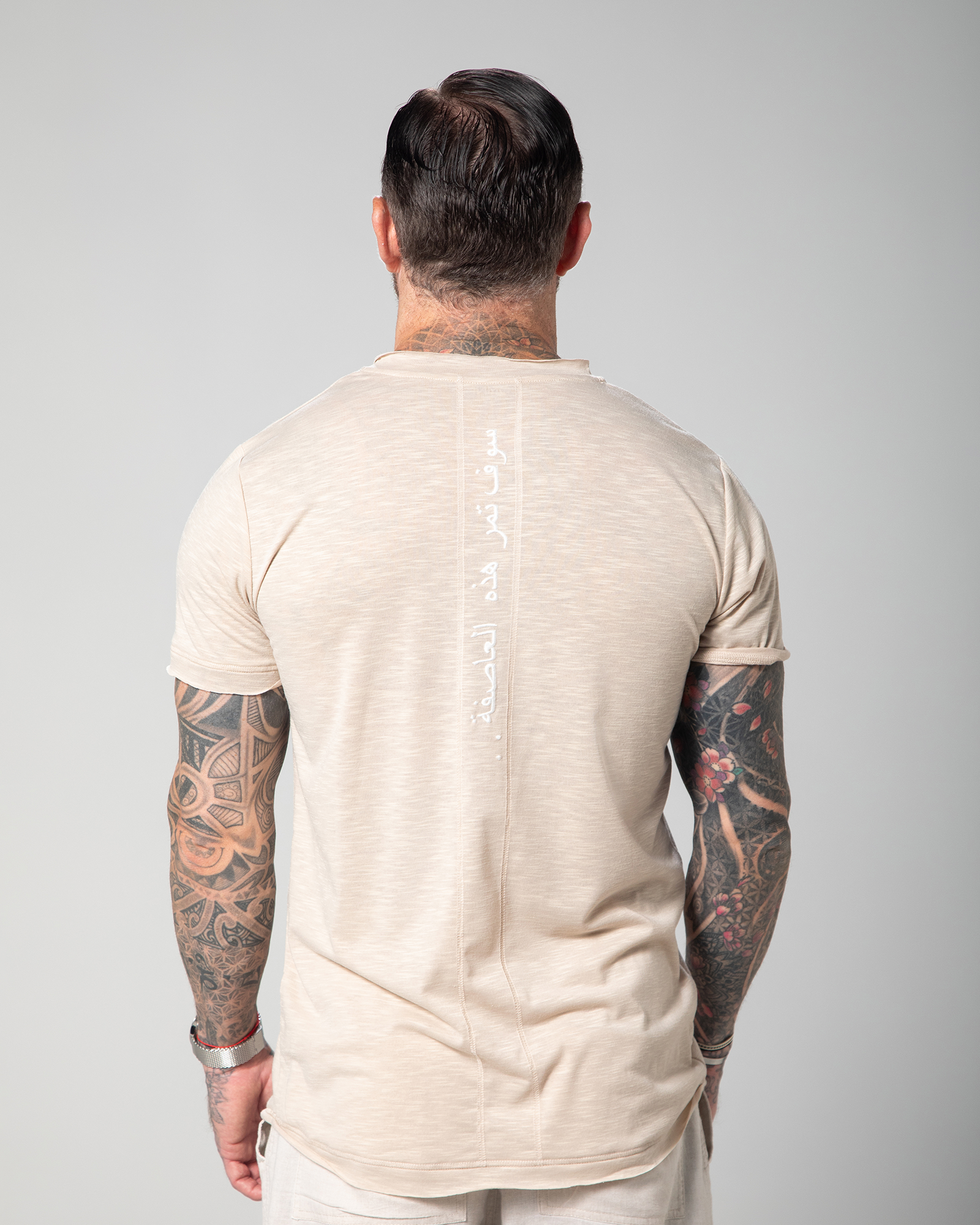 The image depicts the back view of a male model wearing a nude-colored Marbella V-neck T-shirt. The T-shirt is designed with a slub jersey texture, enhancing its breathability and comfort UAE KSA Qatar