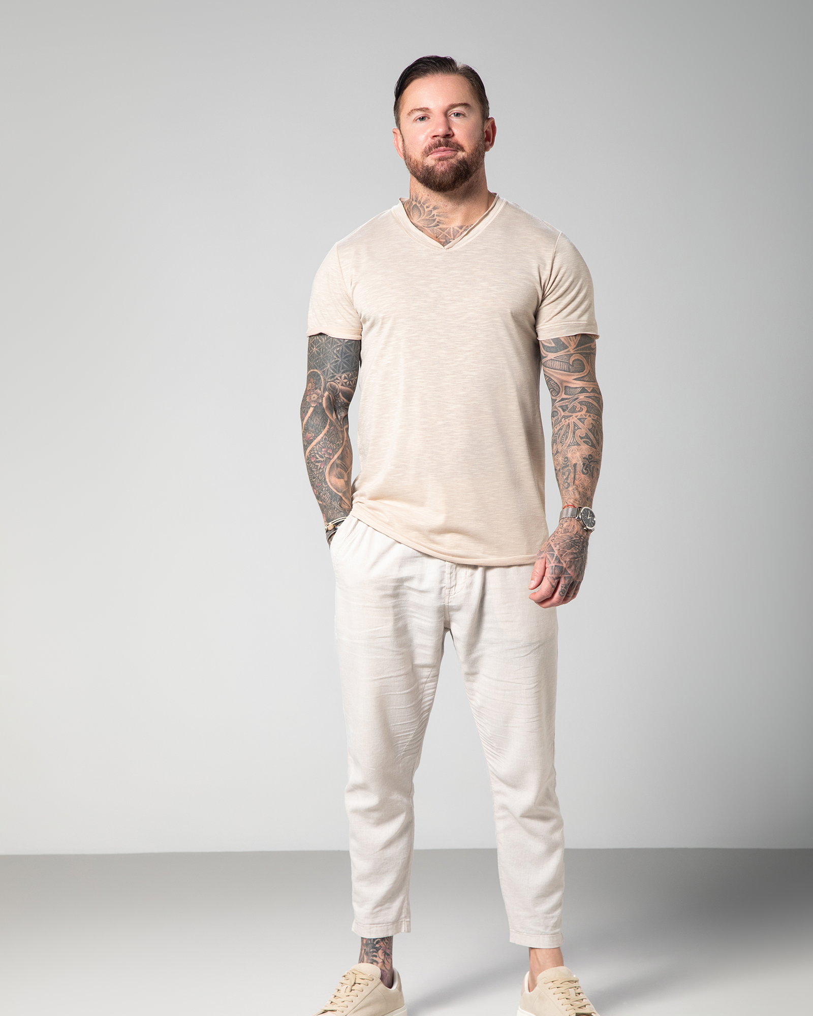 Male model wearing the Marbella nude V-neck T-shirt by Omni The Label, crafted from 100% slub jersey for a breathable, lightweight feel. UAE KSA Qatar