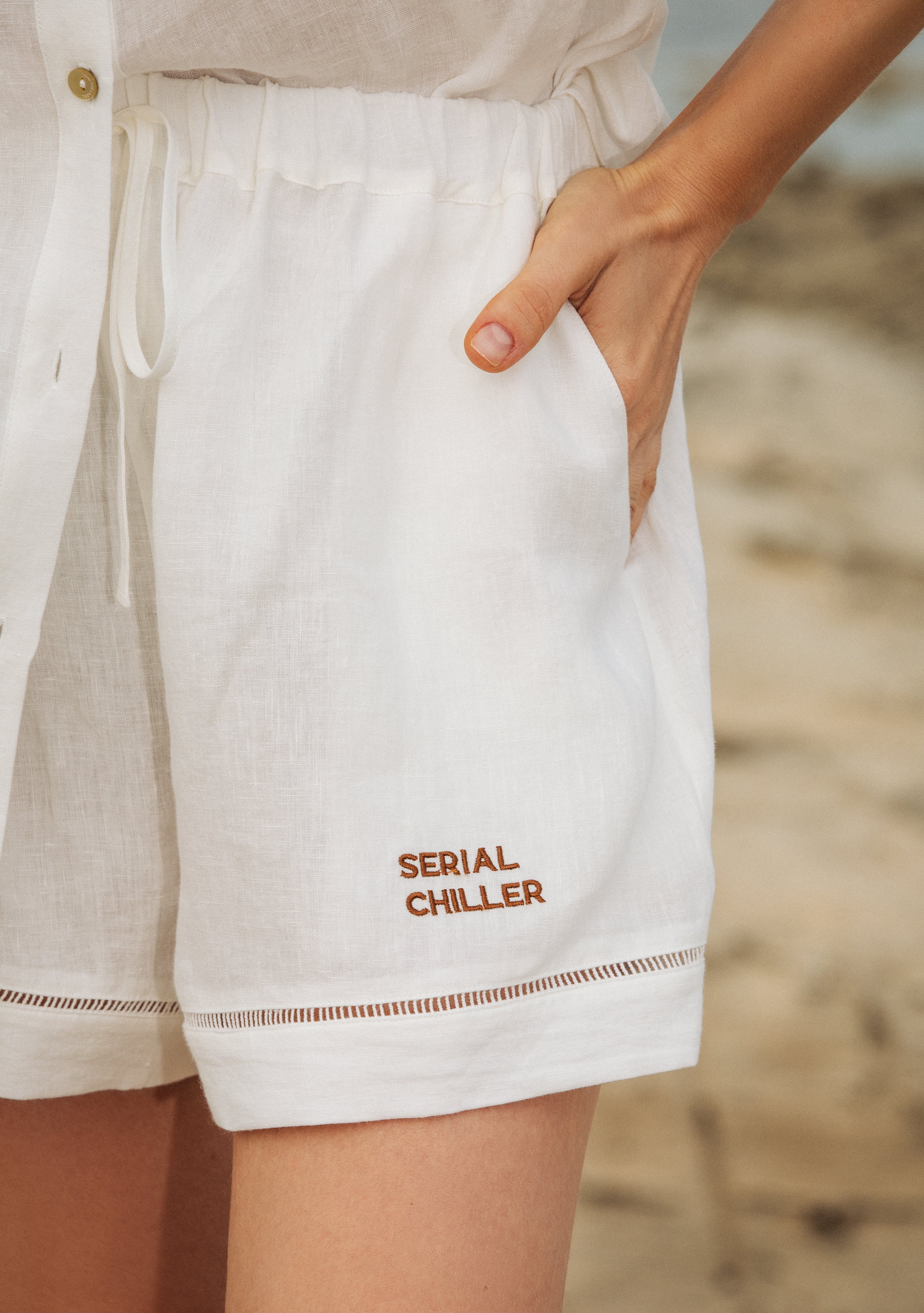Relaxed-fit white linen shorts styled with hands in pockets, capturing ease of movement and breathable design.UAE, KSA, Qatar