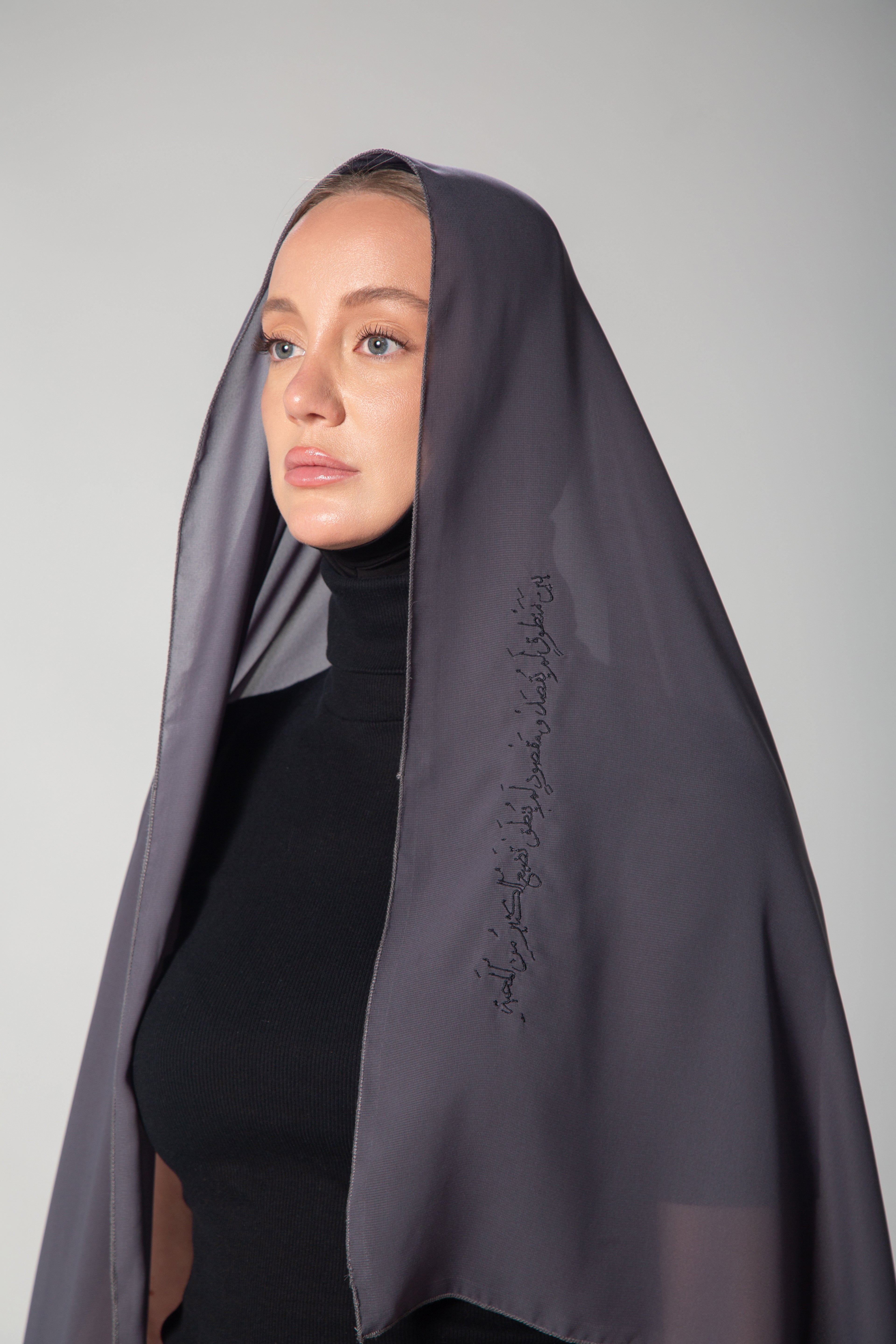 A woman wearing a light gray scarf with black embroidery KSA UAE Qatar