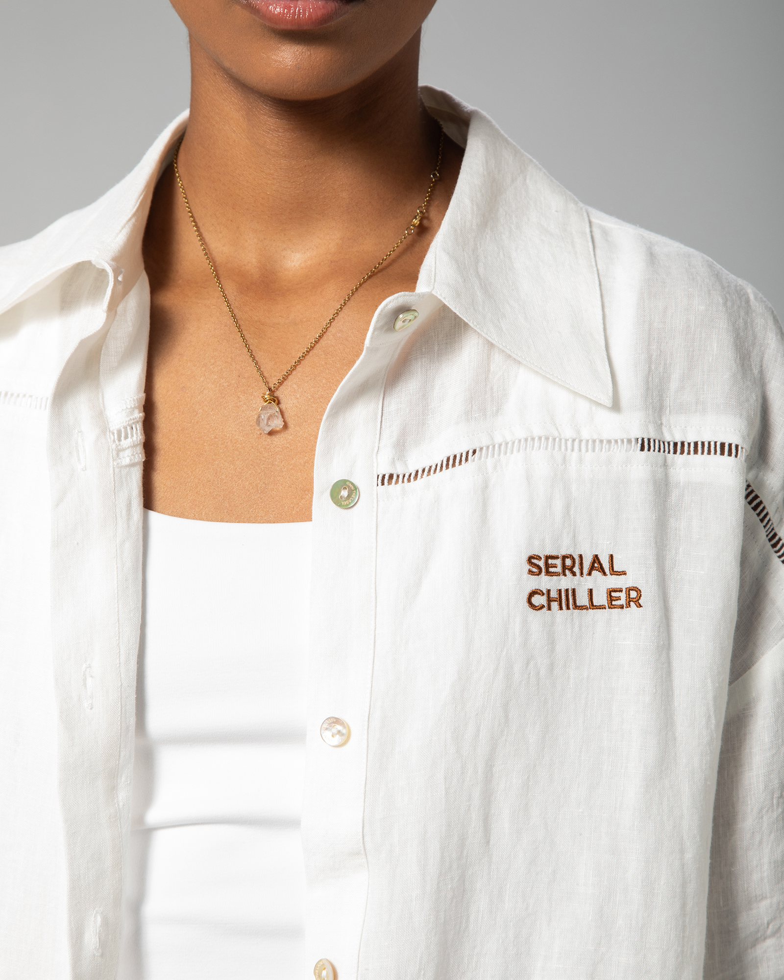Model wearing white short-sleeve linen shirt with dropped shoulders, designed for casual elegance and effortless layering.UAE, KSA, Qatar