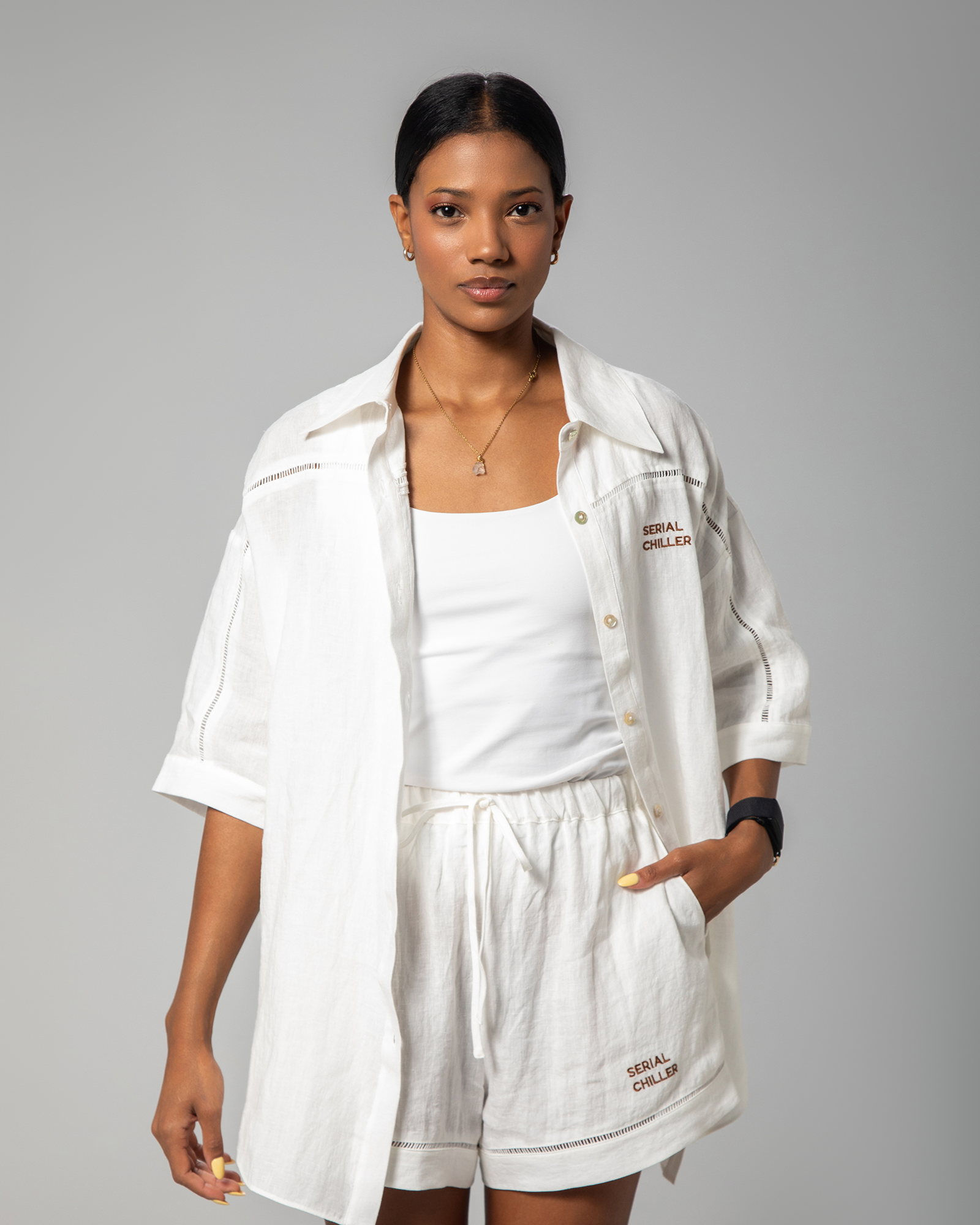 White linen top styled open over a tank top, highlighting the shirt’s airy construction and loose-fit design.UAE, KSA, Qatar