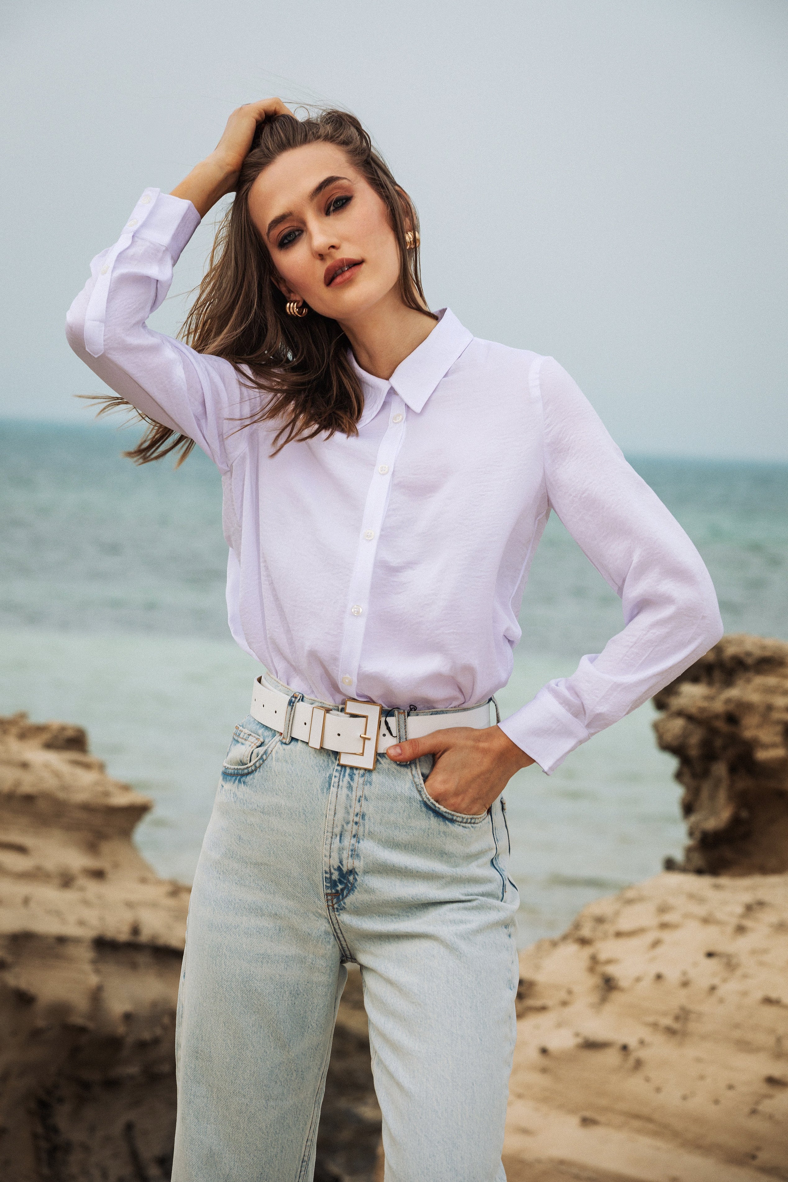 Smiling model in relaxed pose wearing Omni The Label white shirt coastal chic aesthetic UAE KSA Qatar wardrobes