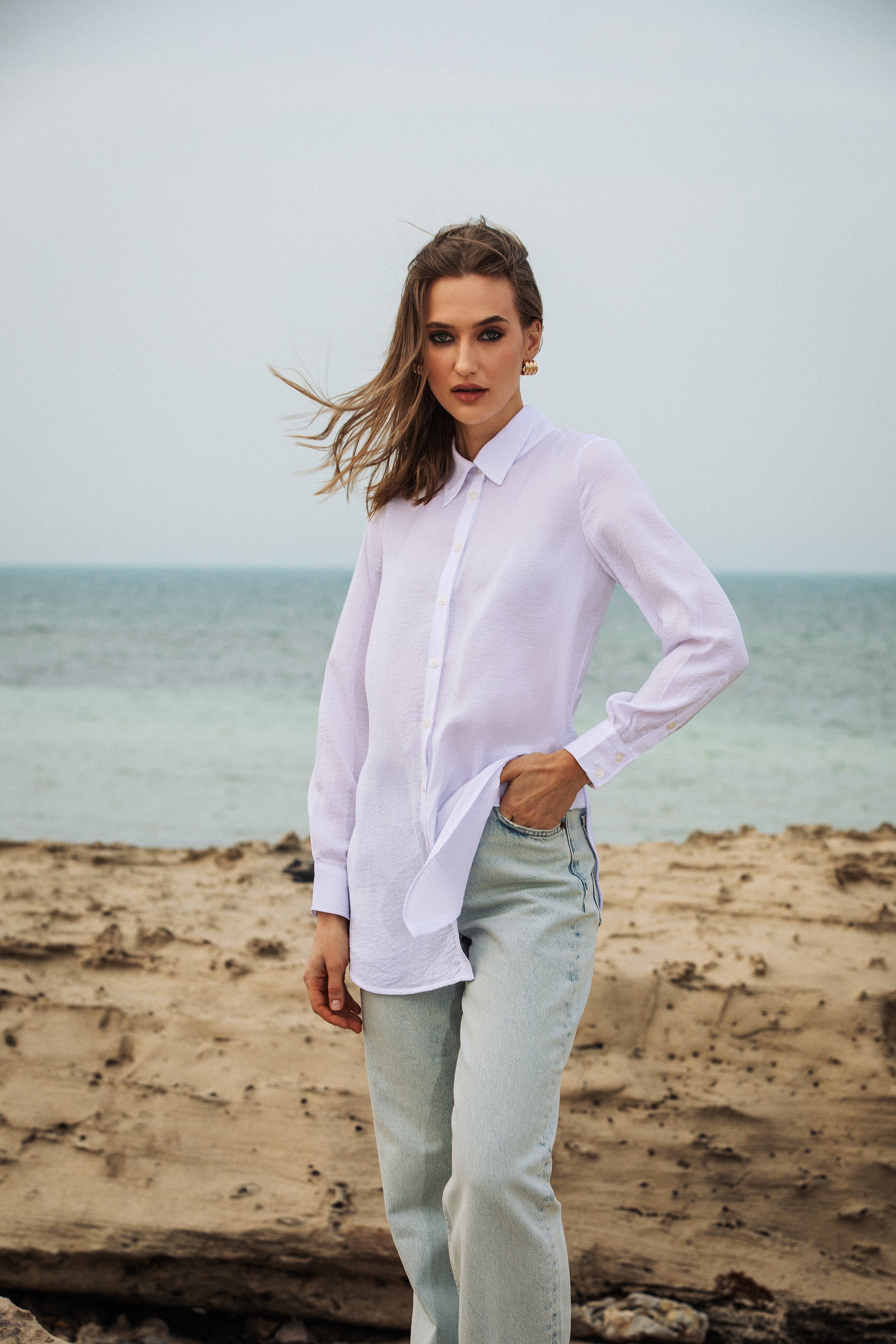 Model facing the ocean wearing embroidered shirt by Omni The Label contemporary modest fashion Qatar UAE KSA