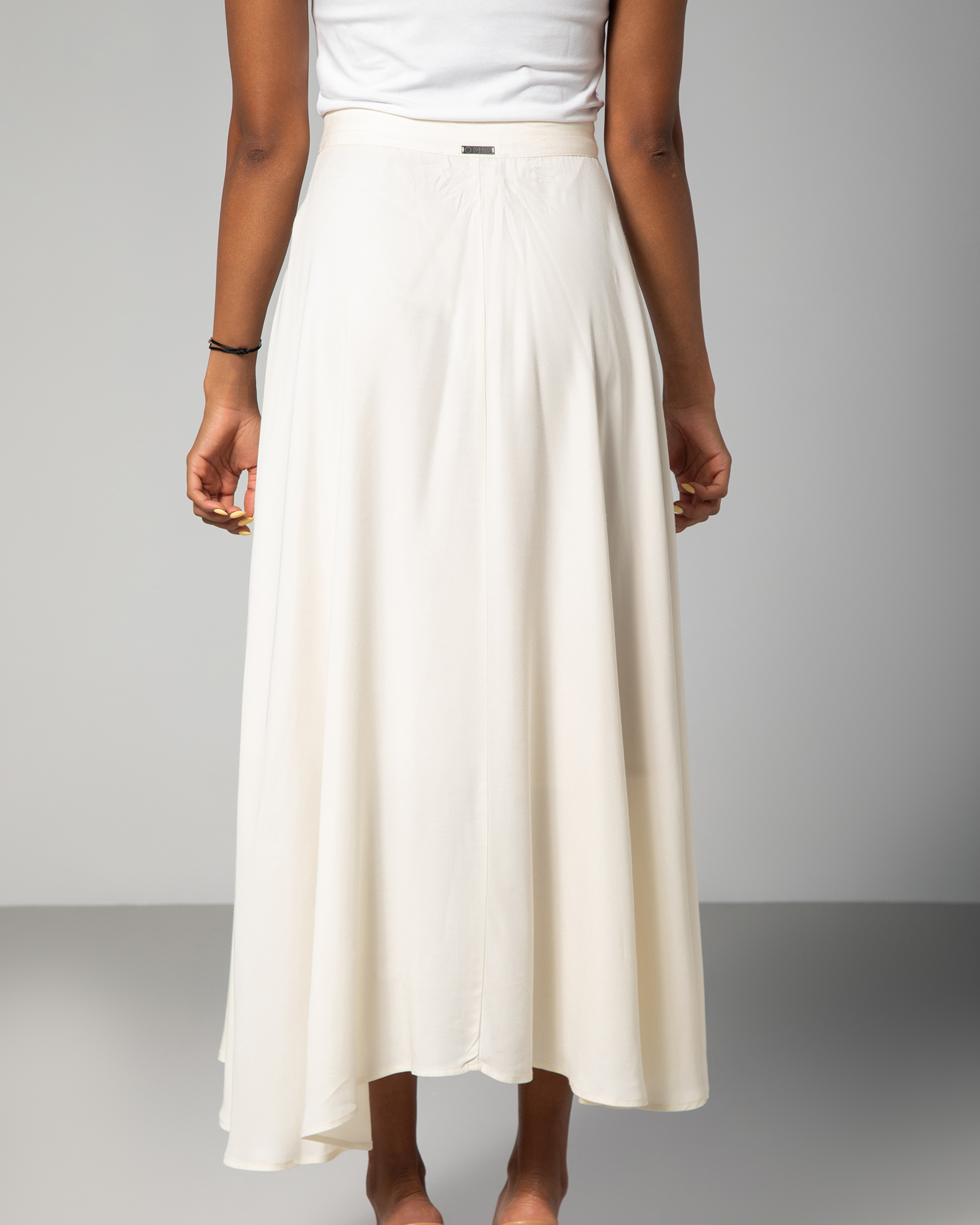 Back view showing length contrast and clean flow of cream midi skirt – UAE, KSA, Qatar