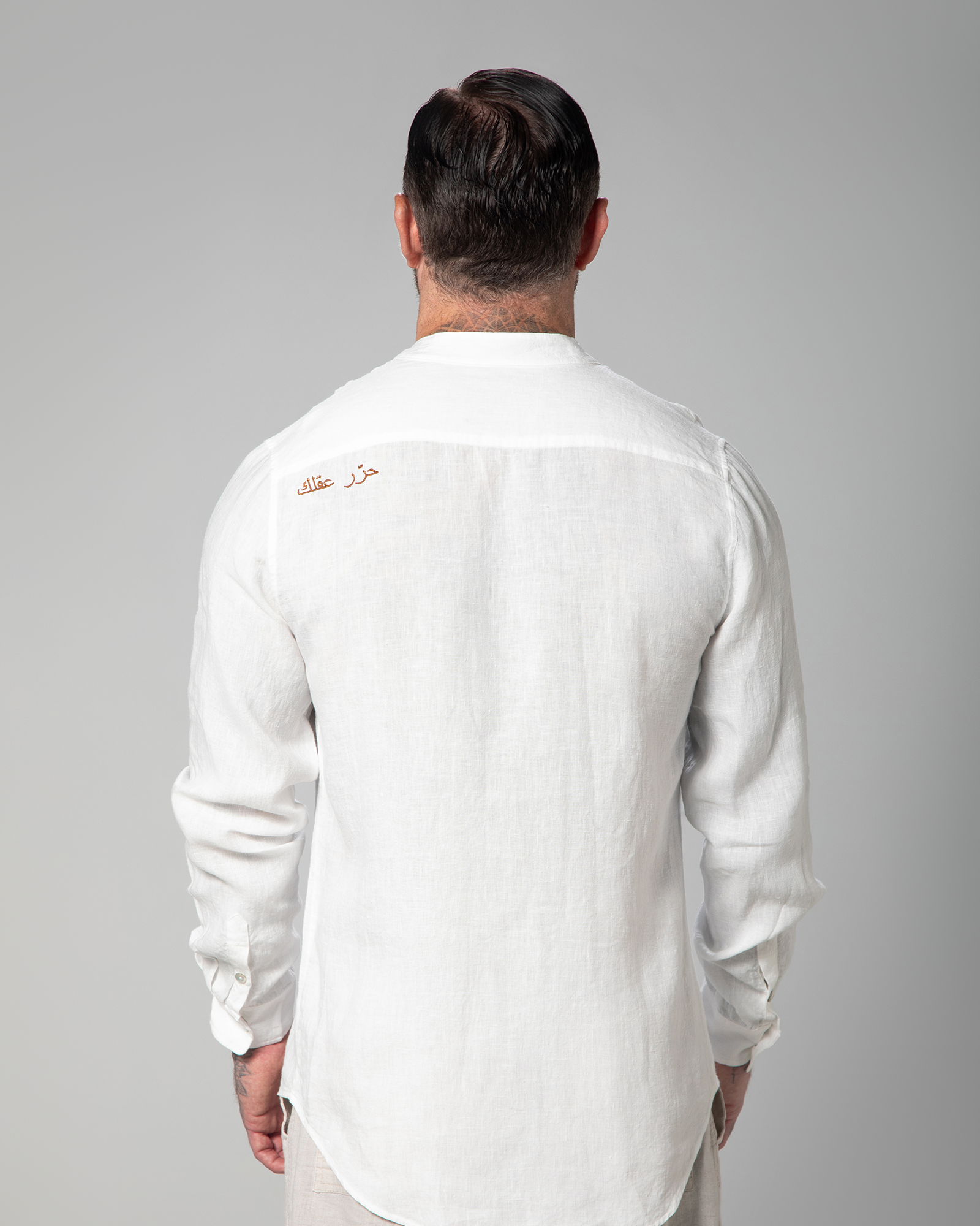 Model turned to show back embroidery on the St. Tropez white linen shirt by Omni The Label – UAE, KSA, Qatar