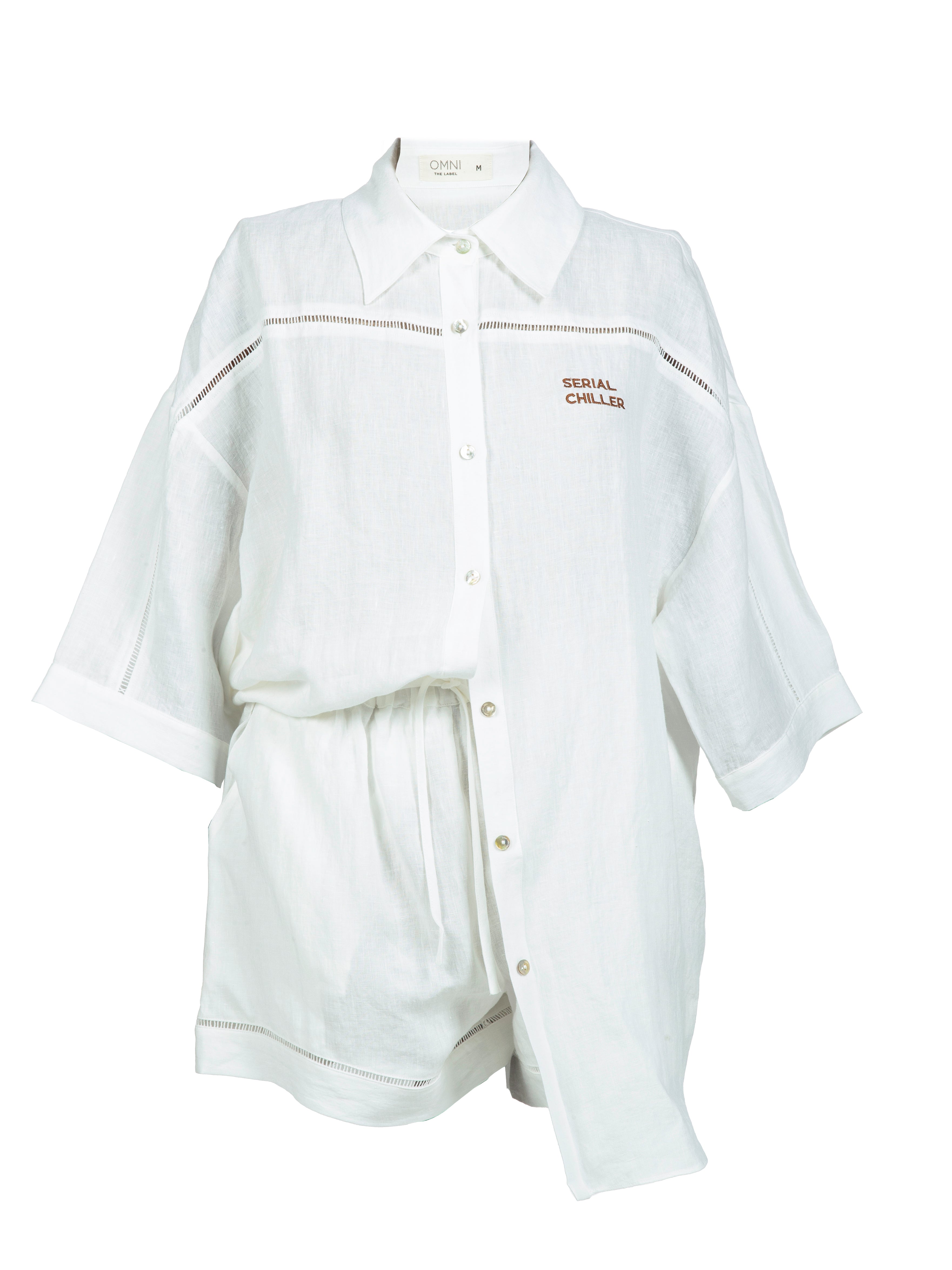 Close-up of Omni The Label’s white linen shirt featuring the “Serial Chiller” embroidery in fine script, highlighting the relaxed and playful summer aesthetic.UAE, KSA, Qatar