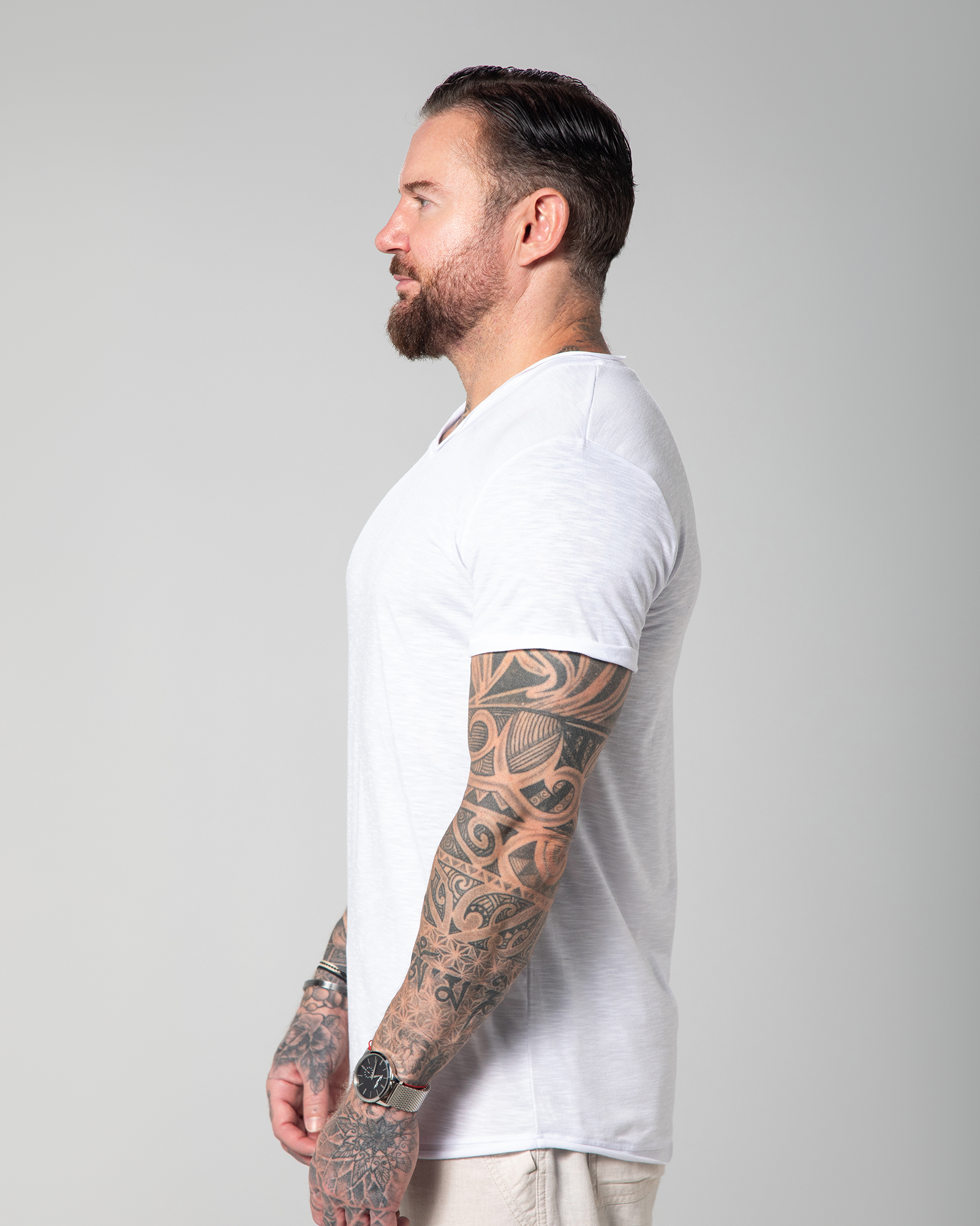 Side profile of a male model wearing Omni The Label’s Marbella white V-neck T-shirt, showcasing the relaxed sleeve cut and slub jersey drape.UAE, KSA, Qatar