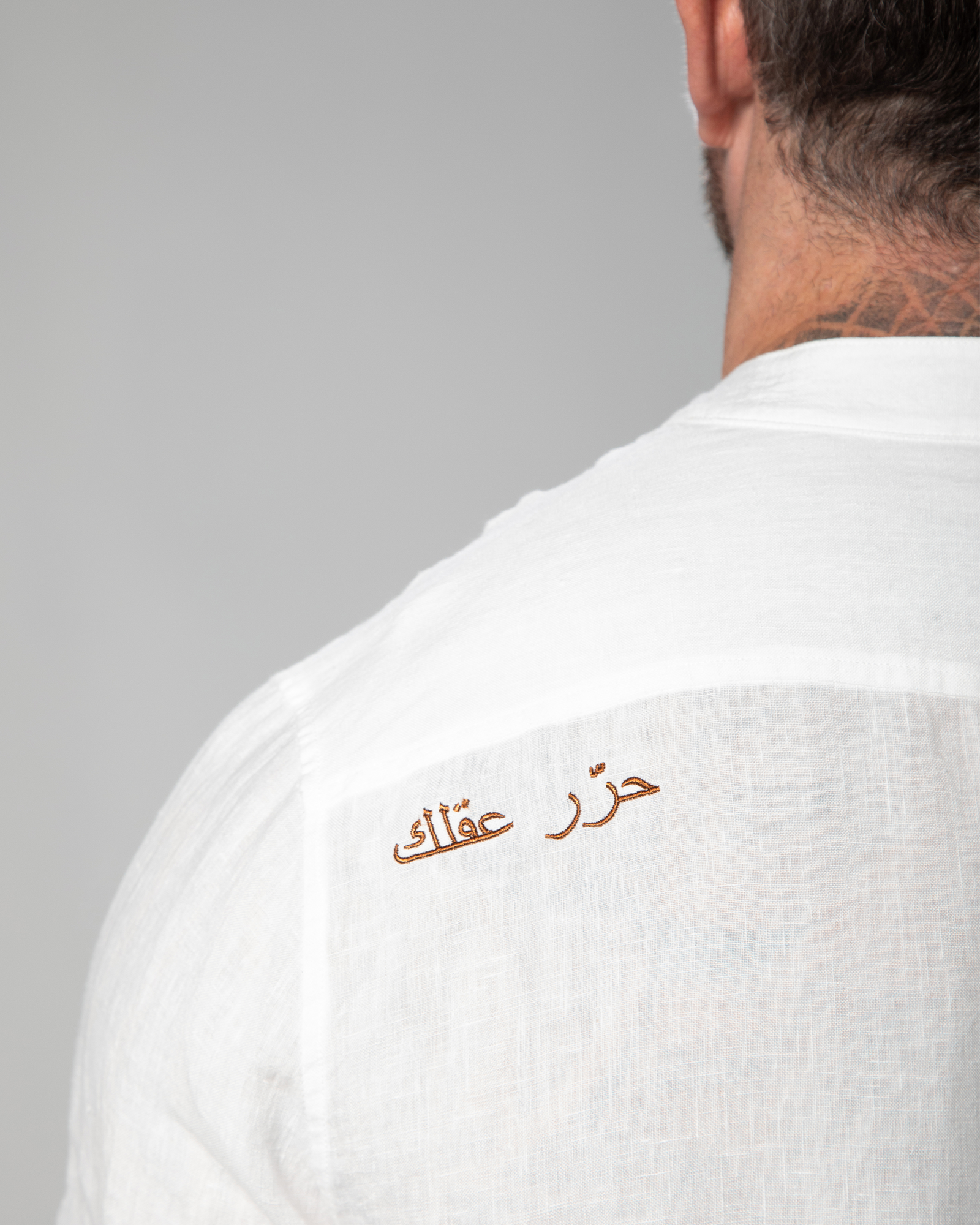 Close-up of Arabic embroidery reading "Free Your Mind" on the white linen shirt by Omni The Label – UAE, KSA, Qatar
