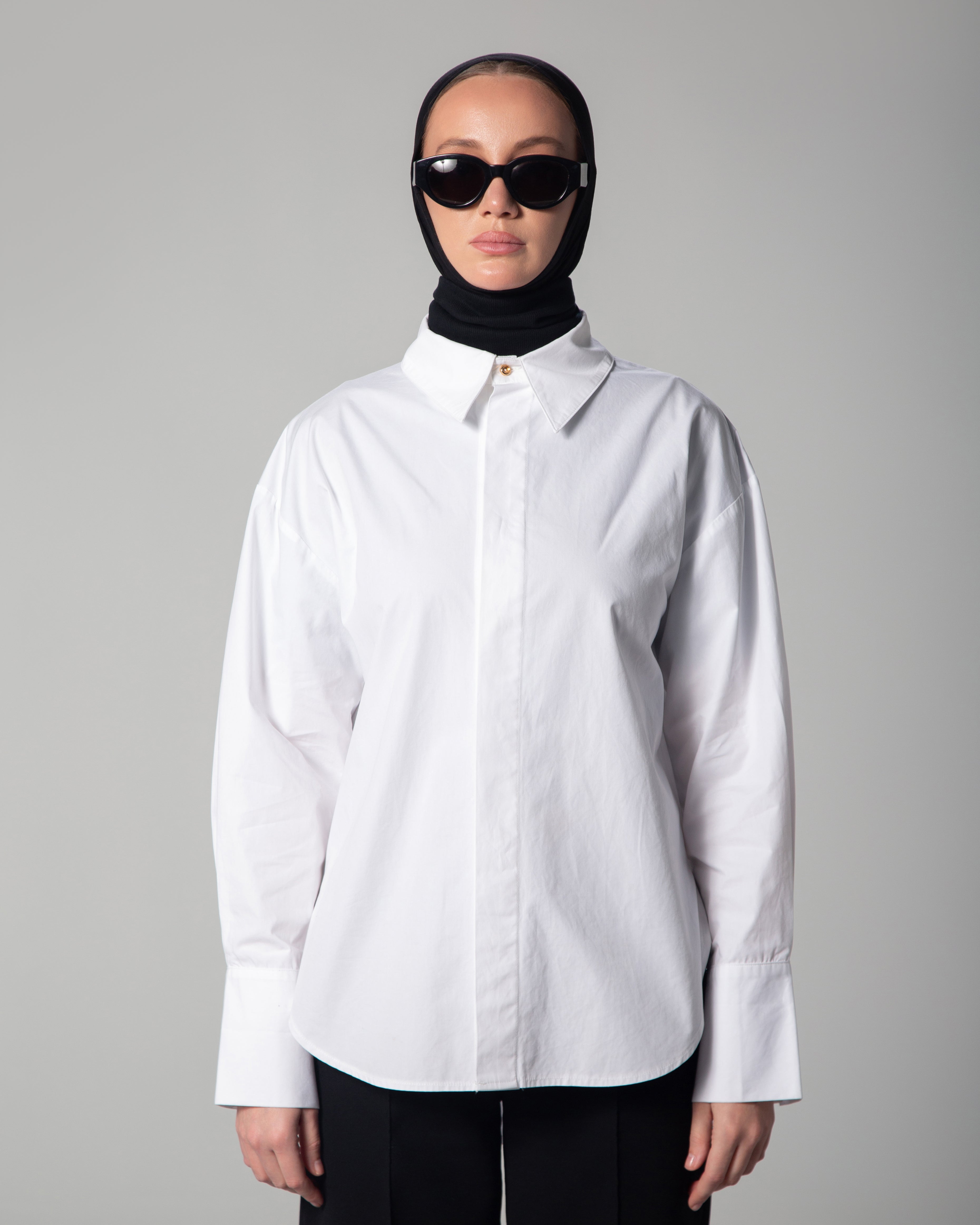 Person wearing a white shirt and black hijab with sunglasses on a gray background uae ksa qatar