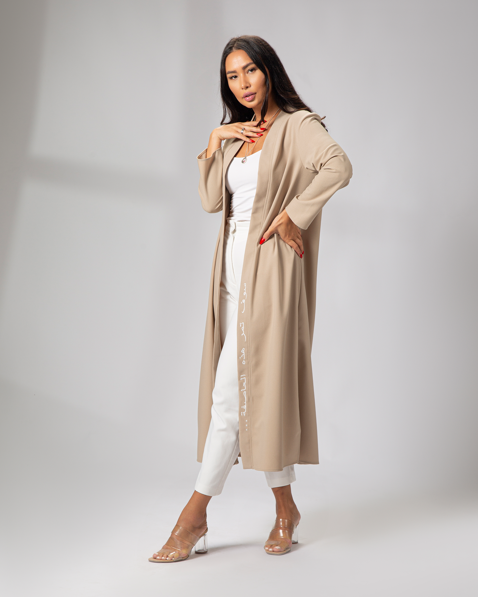 A model wearing a beige long-sleeve kimono with embroidery on the front left side, paired with white trousers and tan shoes uae ksa qatar