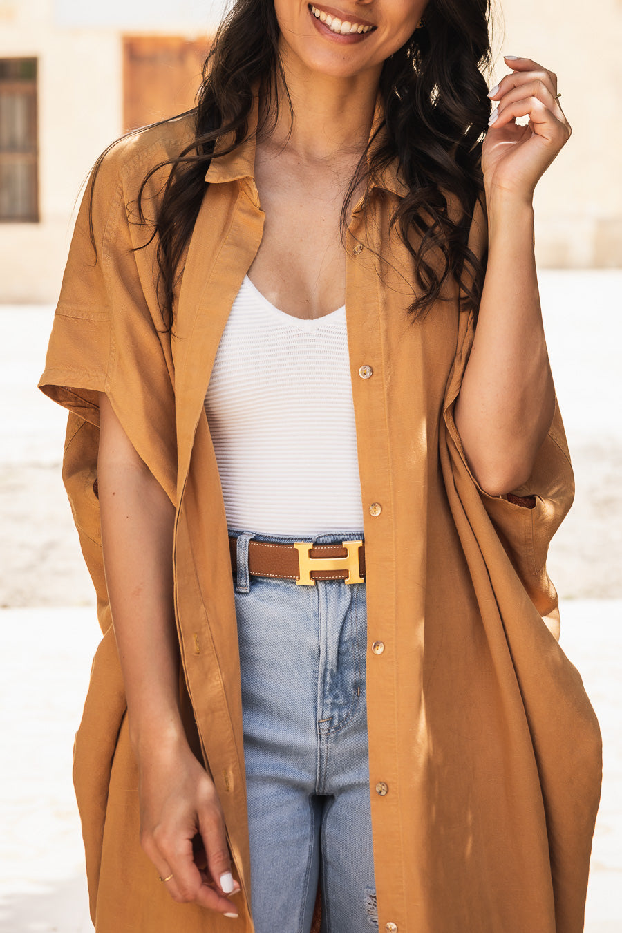 Model styling a camel brown kaftan shirt by Omni The Label with jeans and gold belt Qatar UAE KSA modern modest fashion