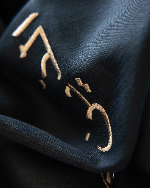 close up of arabic embroidery caligraphy in gold thread on abaya ksa uae qatar kuwait abayas