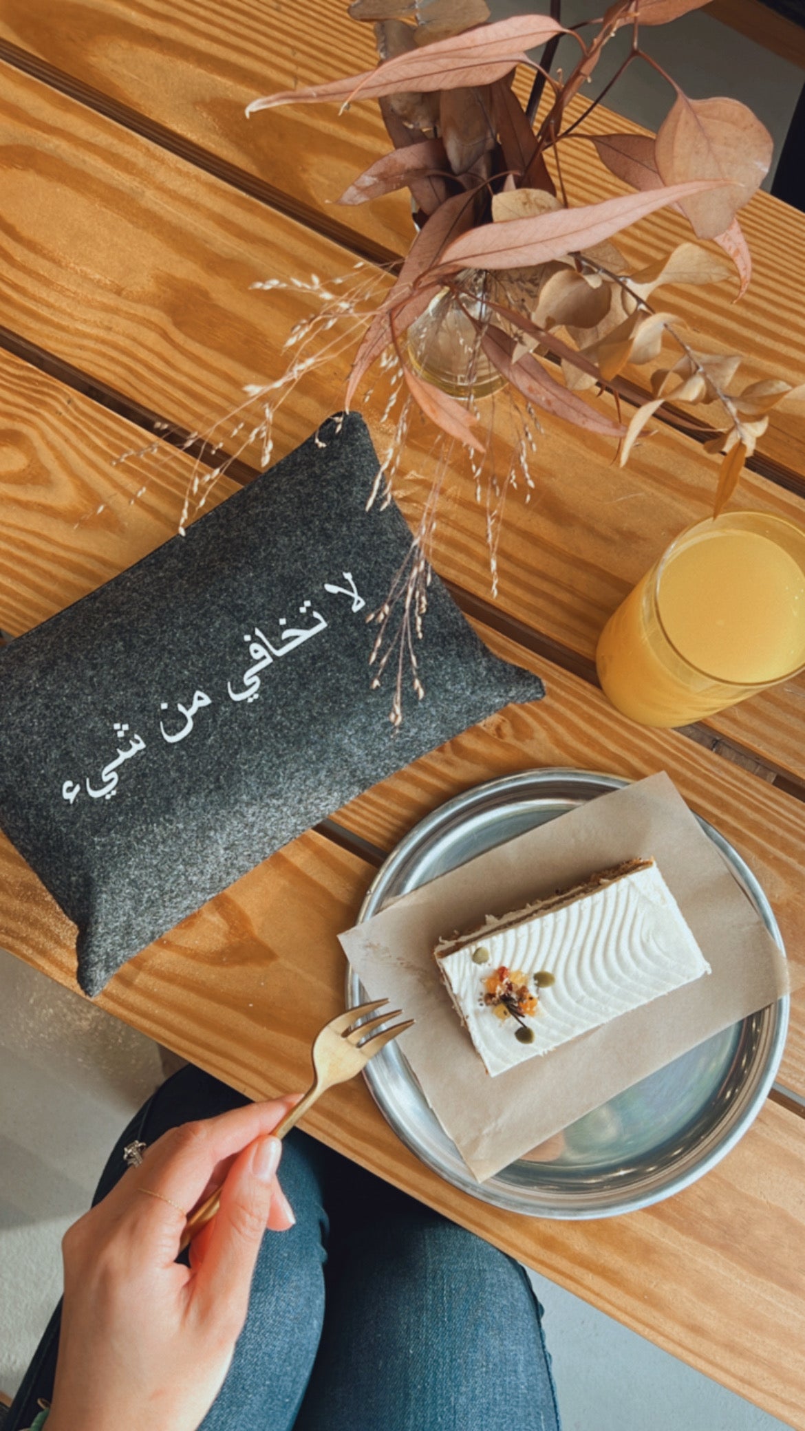 Minimalist grey pouch next to a slice of cake on a rustic wooden table UAE KSA Qatar