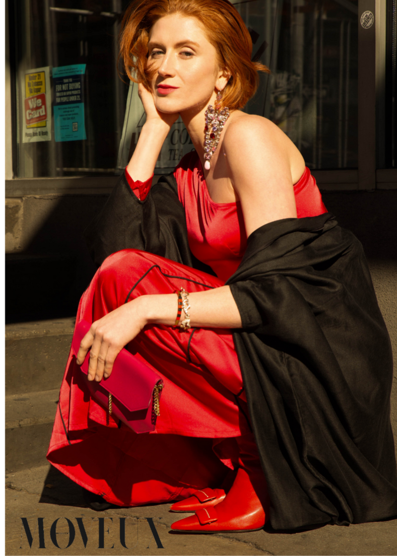 A model on the streets of Manhattan wearing a red dress and a black Omni The Label abaya with Arabic calligraphy embroidery on the back
