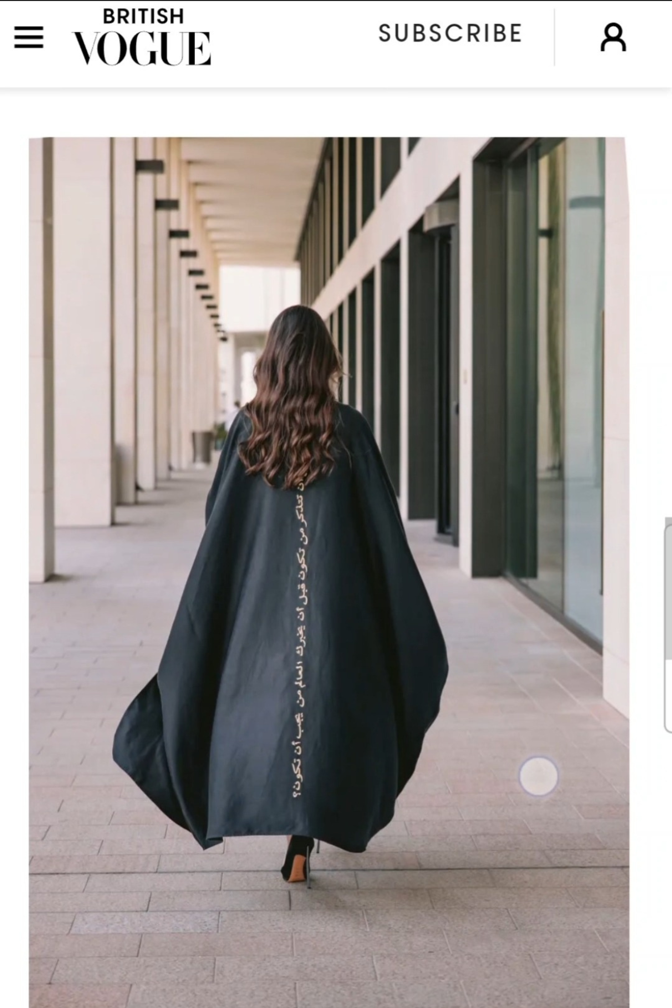 A woman wearing black classic abaya by Omni The Label with Arabic calligraphy embroidery on the back 