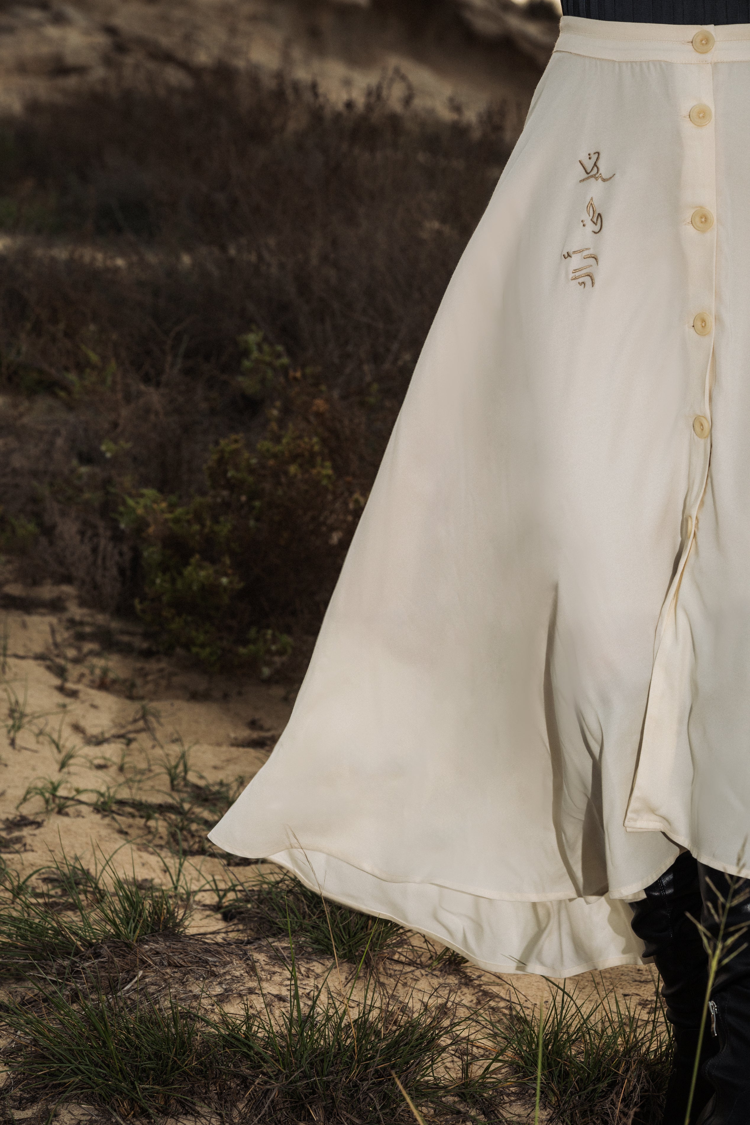 The omni the label skirt in cream white with arabic embroidery on the side and buttons