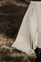 The omni the label skirt in cream white with arabic embroidery on the side and buttons UAE, KSA, Qatar