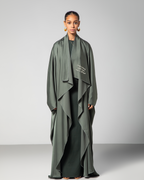 A woman wearing a green flowing abaya with cascading layers and embroidery on the front.UAE Qatar KSA