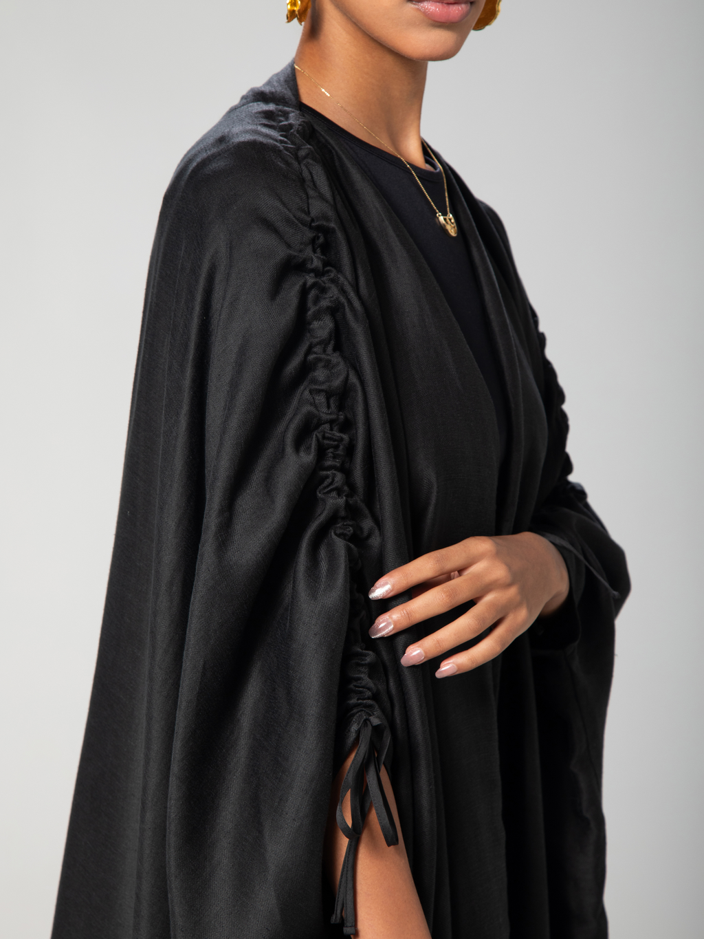 a black abaya with adjiustable sleeves with arabic caligraphy embroidered on the back by omni the label