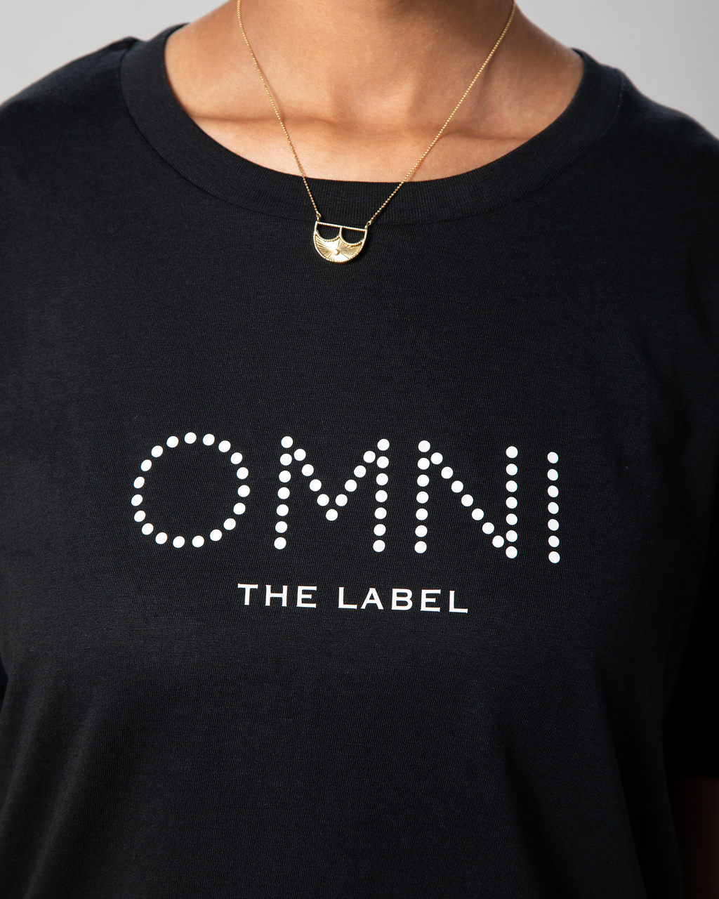 etailed front view of the black T-shirt showing Omni The Label logo printed across the chest in minimalist white font.
