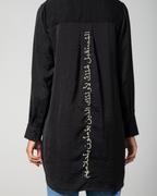 Close-up of the gold-thread Arabic embroidery on the back of Omni The Label’s black shirt – UAE, KSA, Qatar