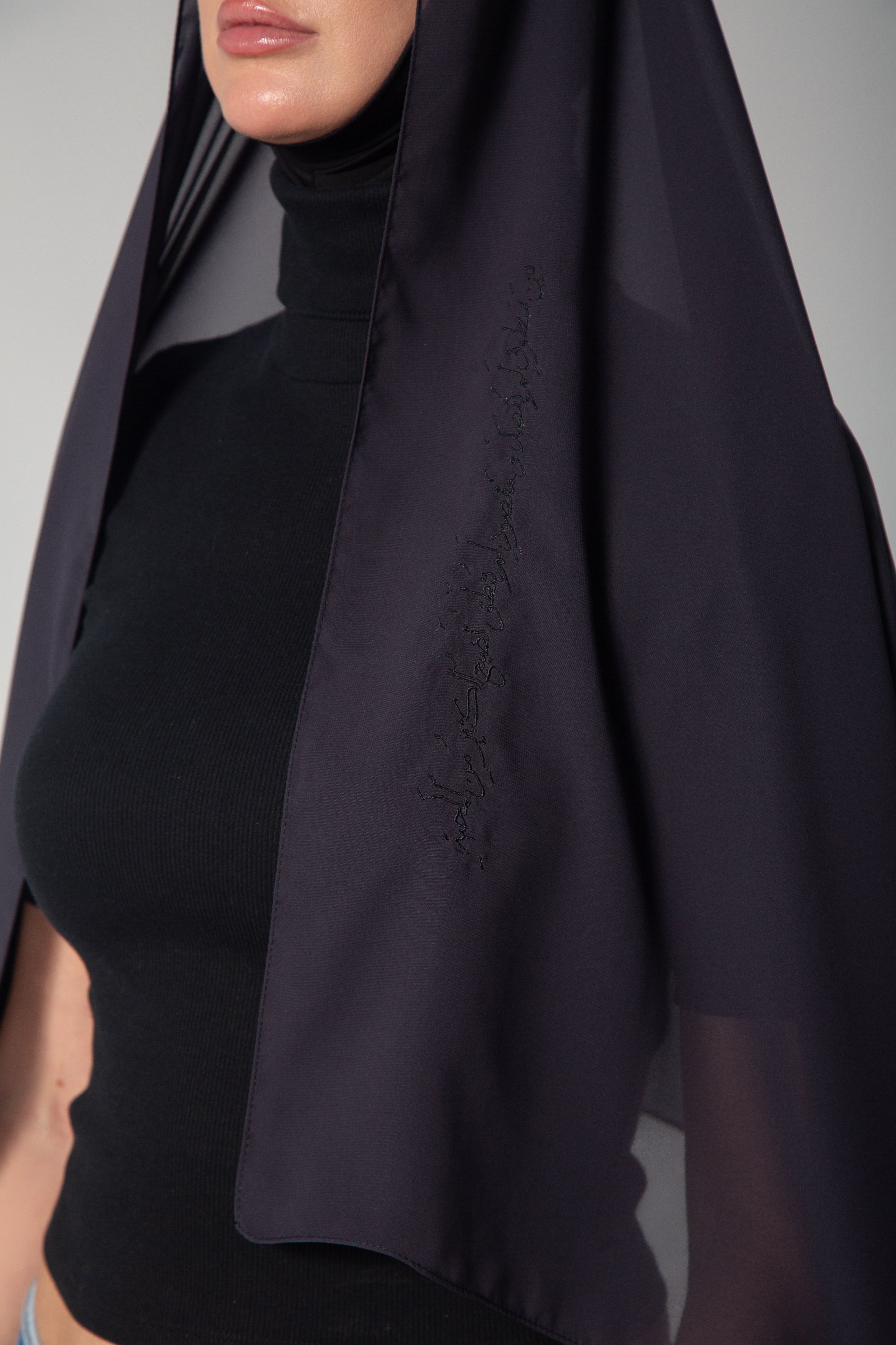  woman wearing a dark gray chiffon sheila with black embroidery KSA UAE Qatar