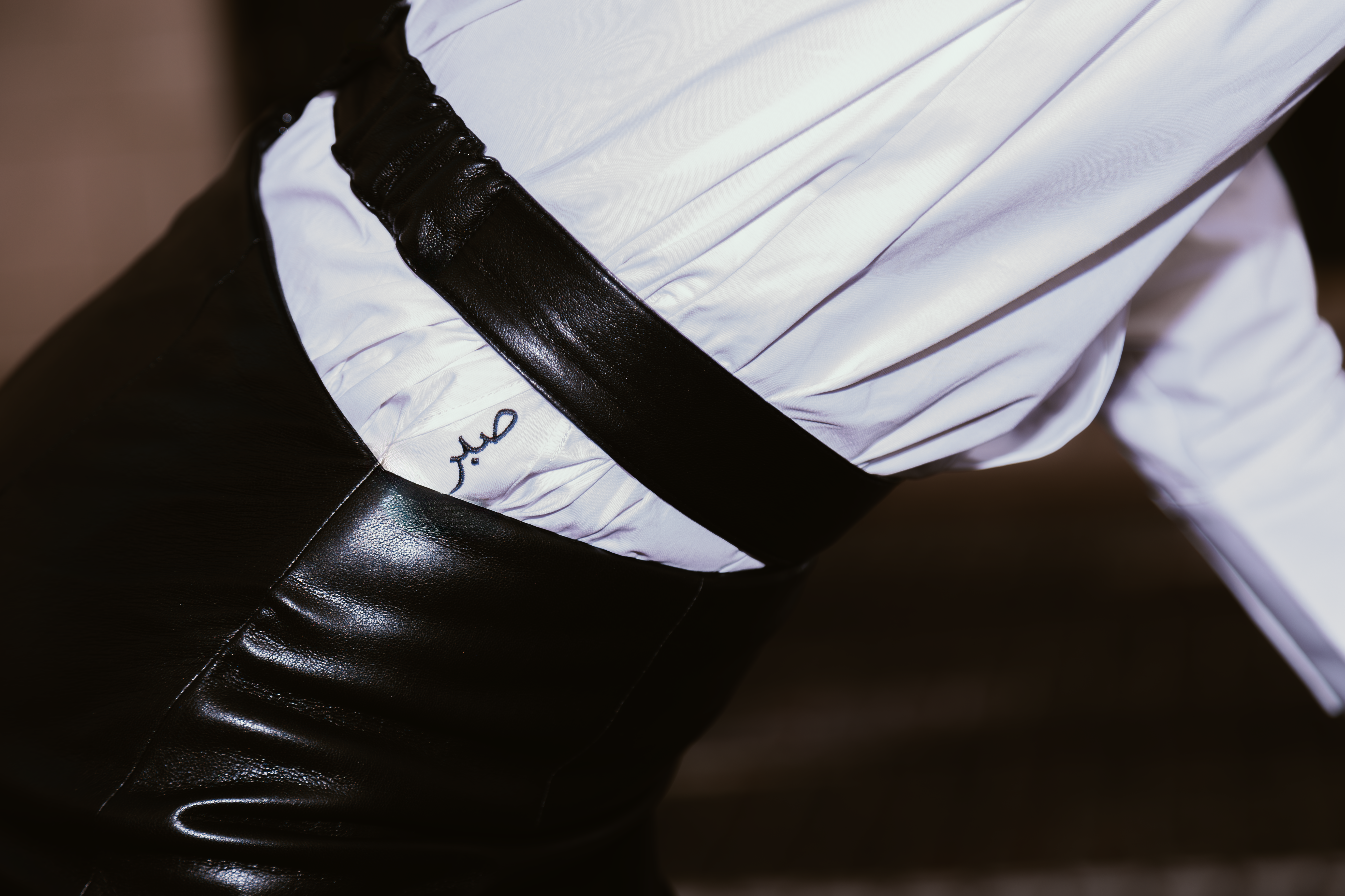 Close-up of a person wearing a white shirt with a black belt.